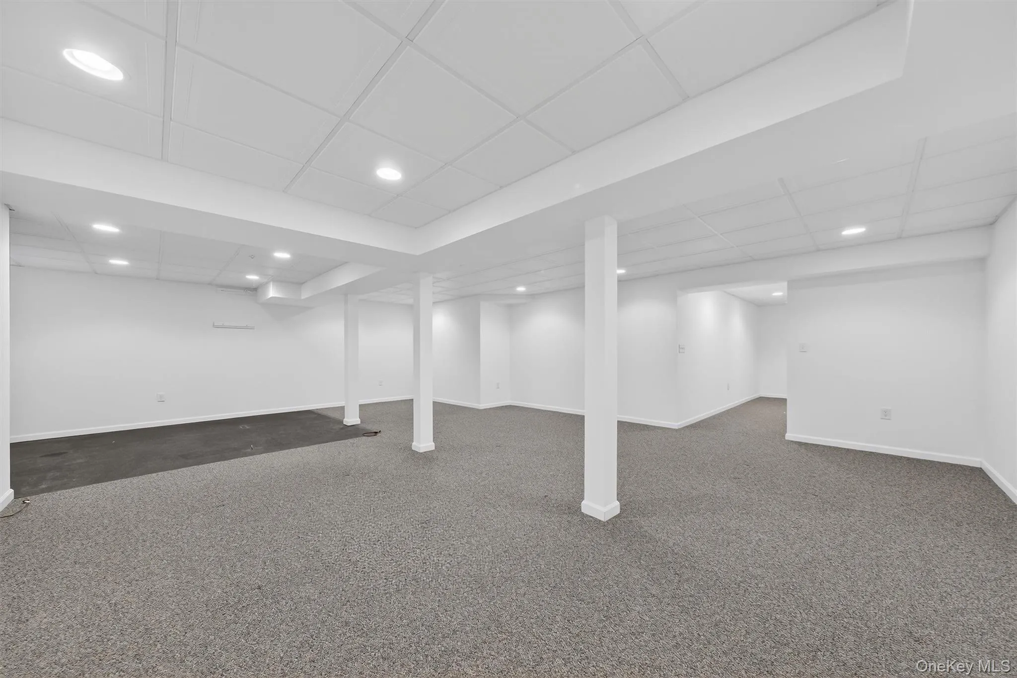 Finished basement with dark carpet, a paneled ceiling, and recessed lighting Finished basement with dark carpet, a paneled ceiling, and recessed lighting