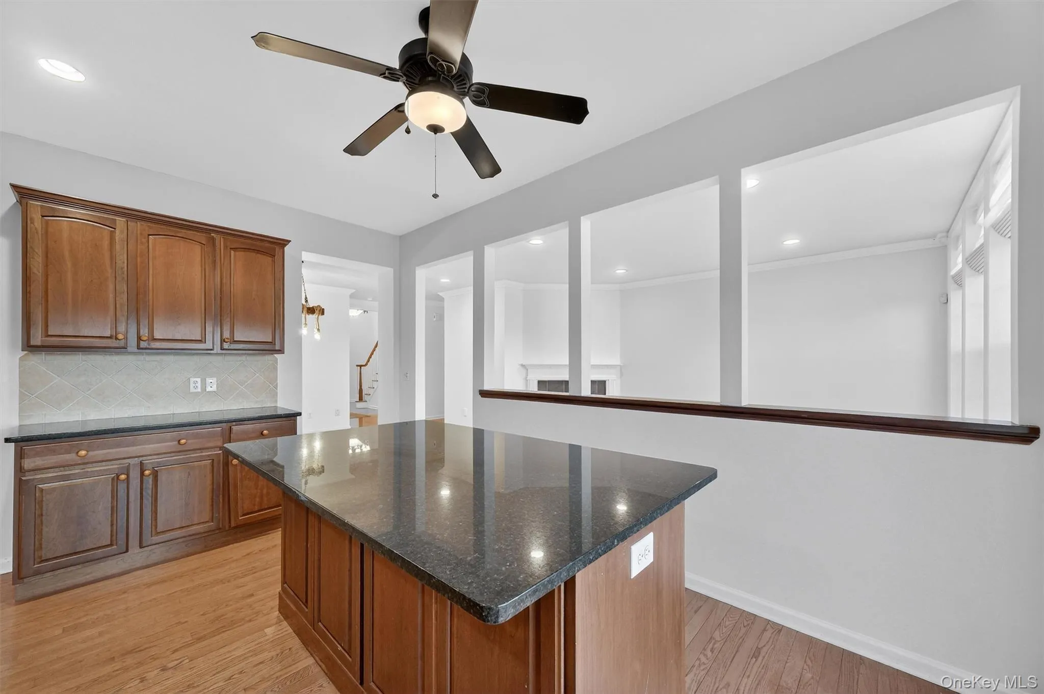 Kitchen with dark stone countertops, light wood-style floors, brown cabinets, and recessed lighting Kitchen with dark stone countertops, light wood-style floors, brown cabinets, and recessed lighting