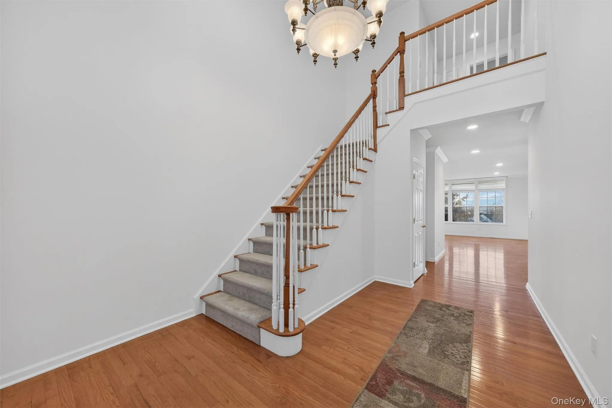 Staircase featuring wood finished floors, a chandelier, a towering ceiling, and recessed lighting Staircase featuring wood finished floors, a chandelier, a towering ceiling, and recessed lighting