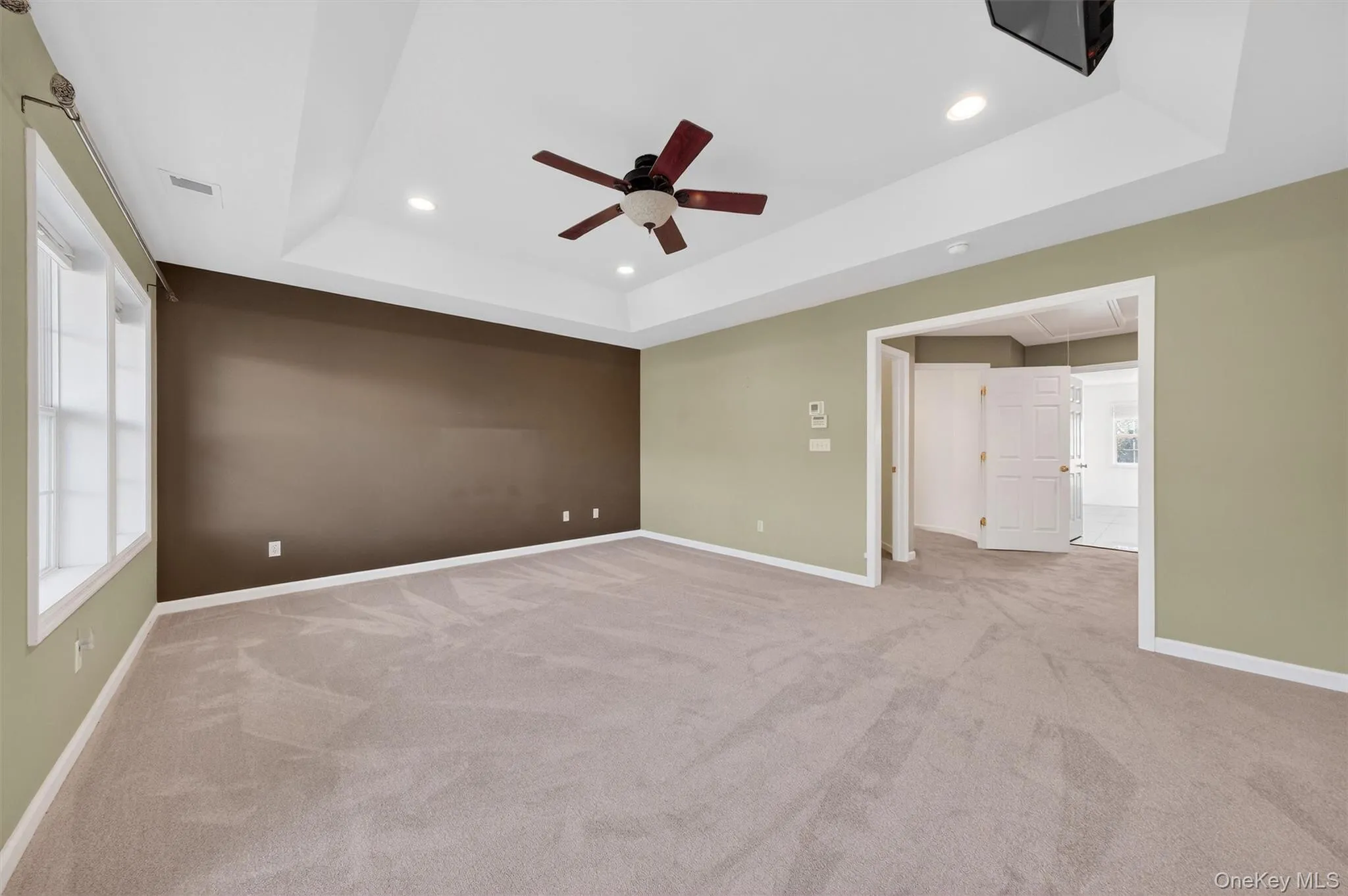 Empty room featuring attic access, light carpet, a tray ceiling, recessed lighting, and ceiling fan Empty room featuring attic access, light carpet, a tray ceiling, recessed lighting, and ceiling fan
