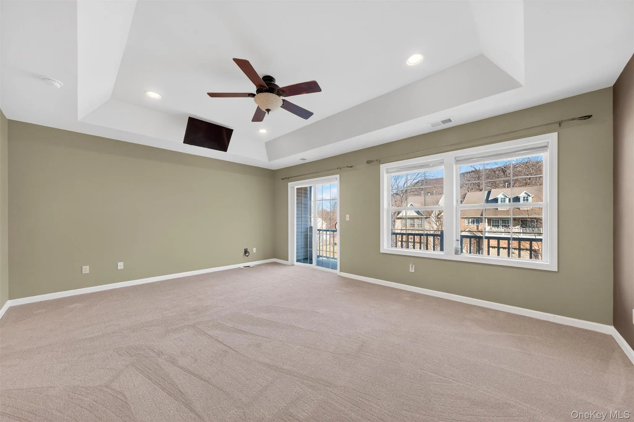 Empty room with a tray ceiling, light carpet, recessed lighting, and a ceiling fan Empty room with a tray ceiling, light carpet, recessed lighting, and a ceiling fan