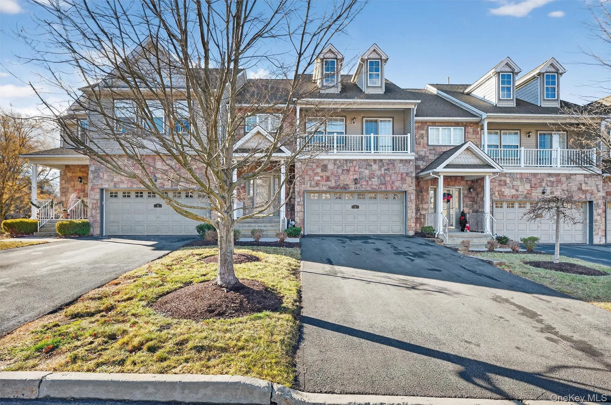 Traditional home with a balcony, asphalt driveway, stone siding, and an attached garage Traditional home with a balcony, asphalt driveway, stone siding, and an attached garage