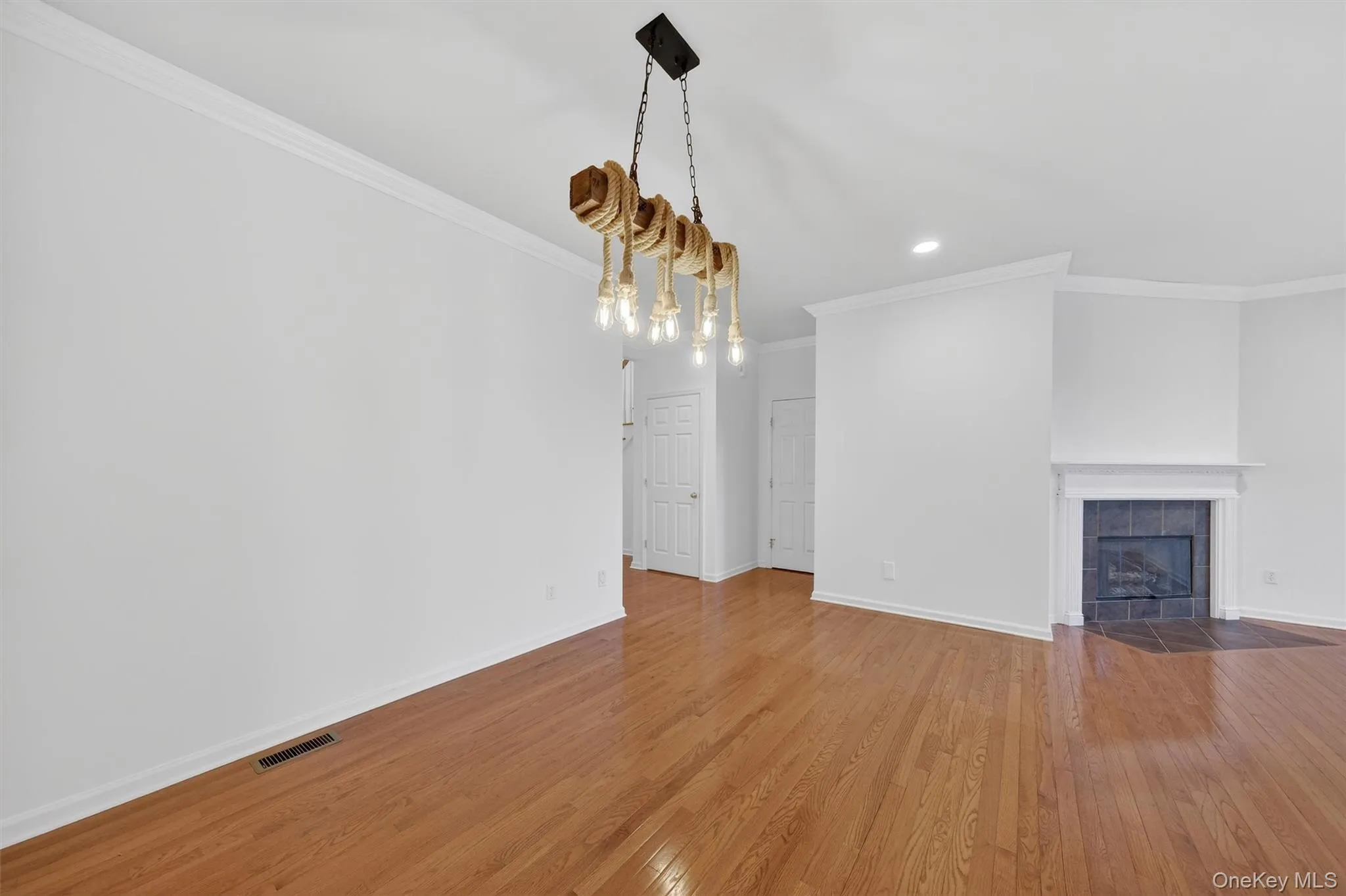 Unfurnished living room featuring ornamental molding, hardwood / wood-style flooring, a tile fireplace, and recessed lighting Unfurnished living room featuring ornamental molding, hardwood / wood-style flooring, a tile fireplace, and recessed lighting
