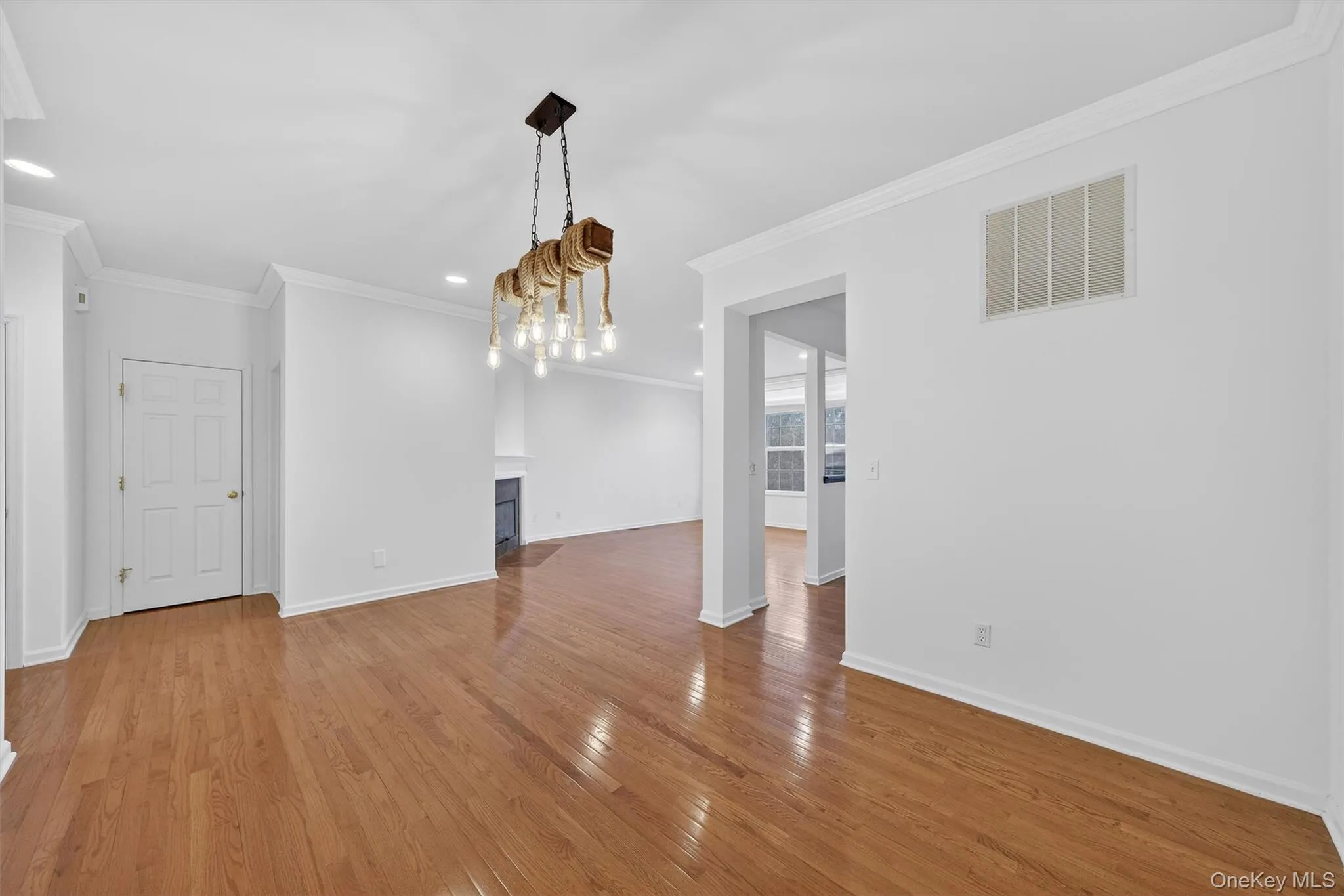 Unfurnished dining area with a fireplace with flush hearth, ornamental molding, hardwood / wood-style flooring, and recessed lighting Unfurnished dining area with a fireplace with flush hearth, ornamental molding, hardwood / wood-style flooring, and recessed lighting