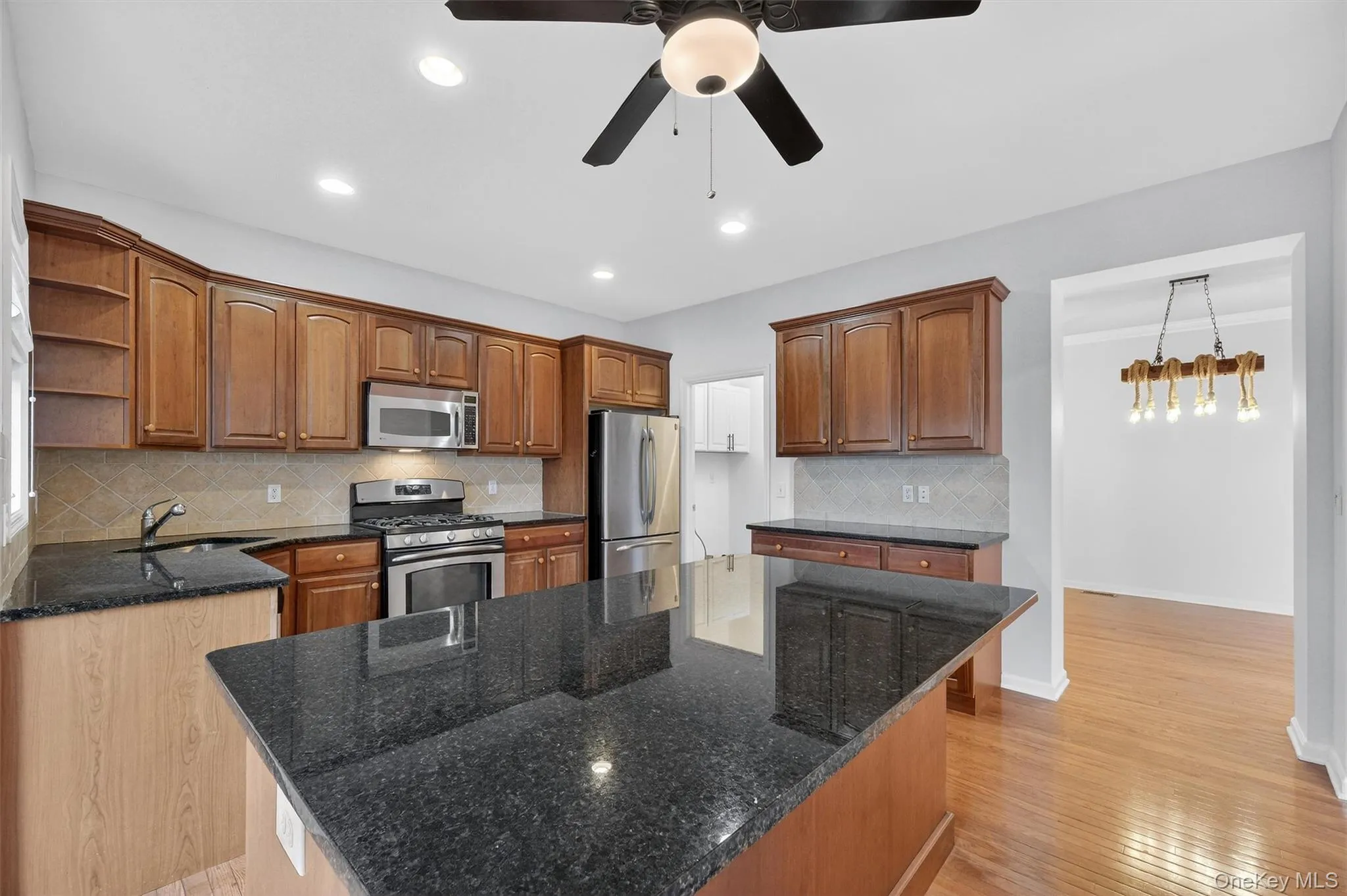 Kitchen featuring appliances with stainless steel finishes, dark stone countertops, open shelves, tasteful backsplash, and recessed lighting Kitchen featuring appliances with stainless steel finishes, dark stone countertops, open shelves, tasteful backsplash, and recessed lighting