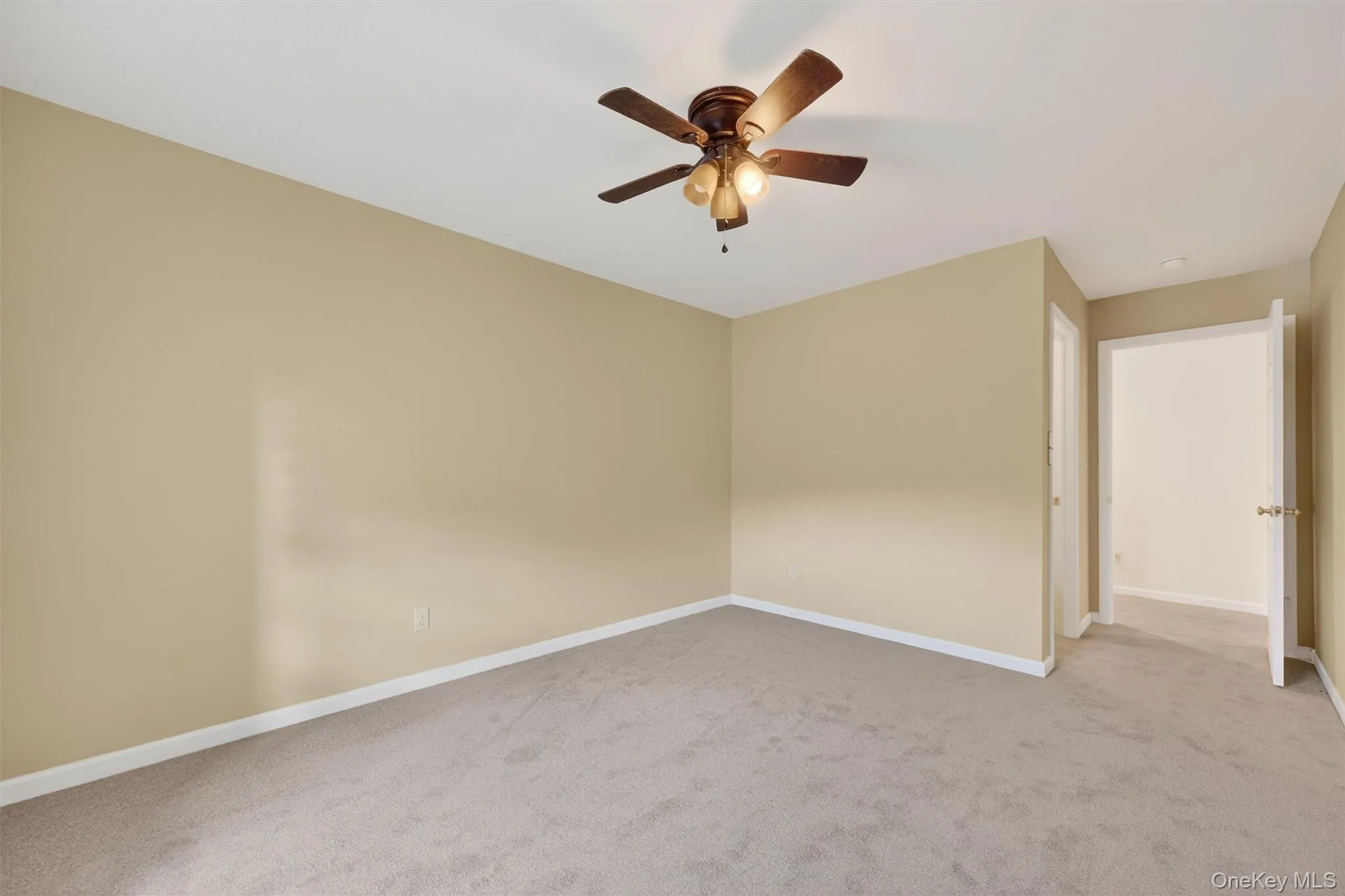 Unfurnished room with light colored carpet and a ceiling fan Unfurnished room with light colored carpet and a ceiling fan