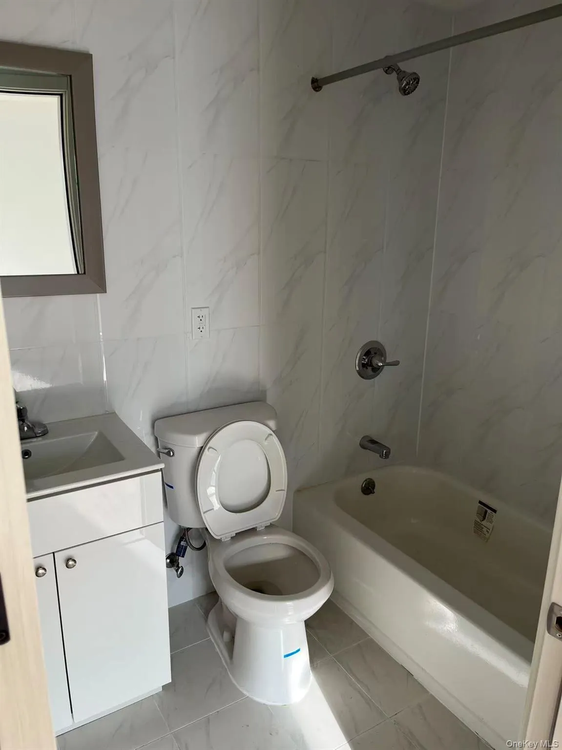 Full bath with tile walls, vanity, shower / bathtub combination, and light marble finish flooring Full bath with tile walls, vanity, shower / bathtub combination, and light marble finish flooring
