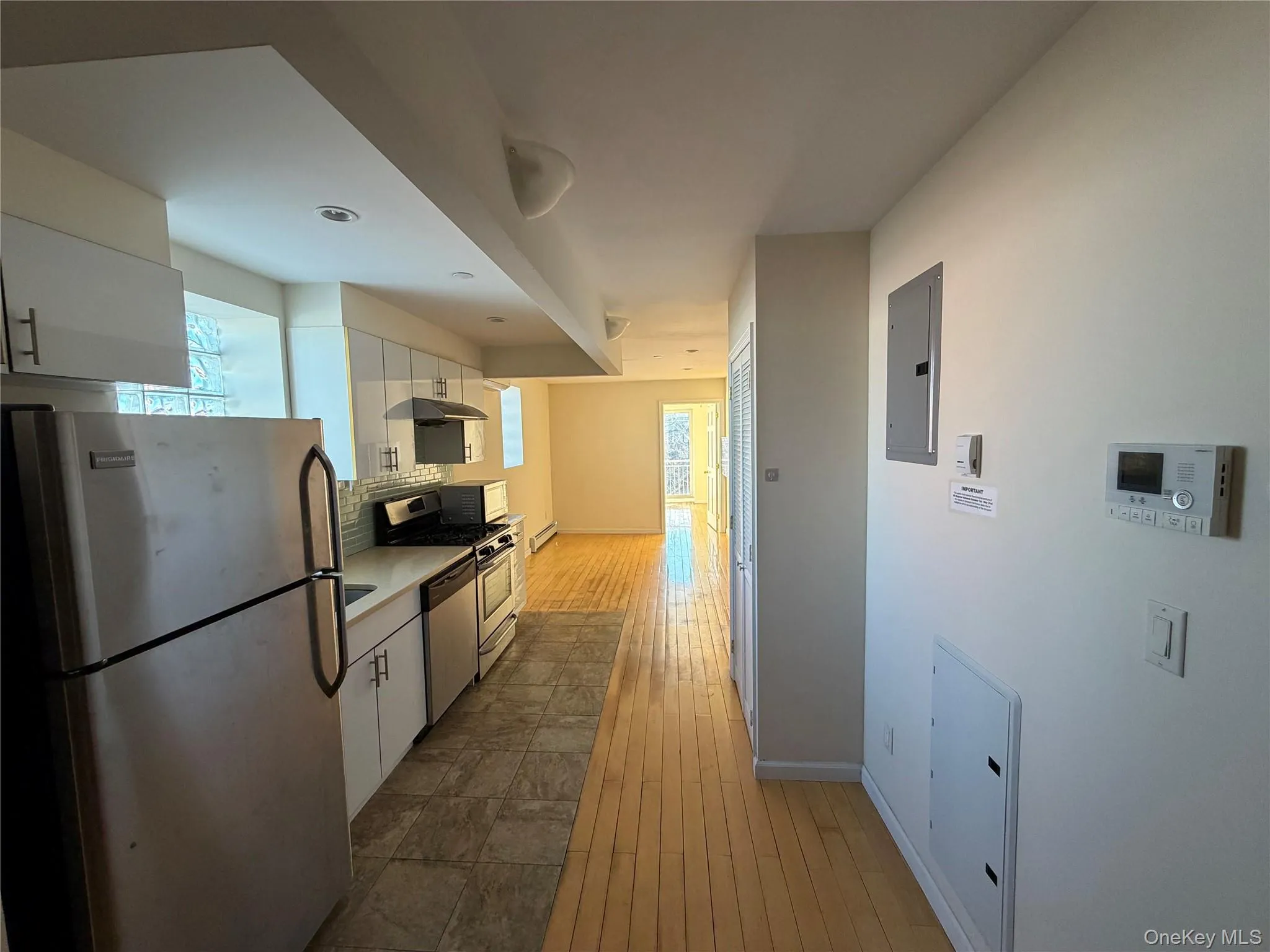 Kitchen with appliances with stainless steel finishes, white cabinets, light countertops, dark wood-style floors, and electric panel Kitchen with appliances with stainless steel finishes, white cabinets, light countertops, dark wood-style floors, and electric panel