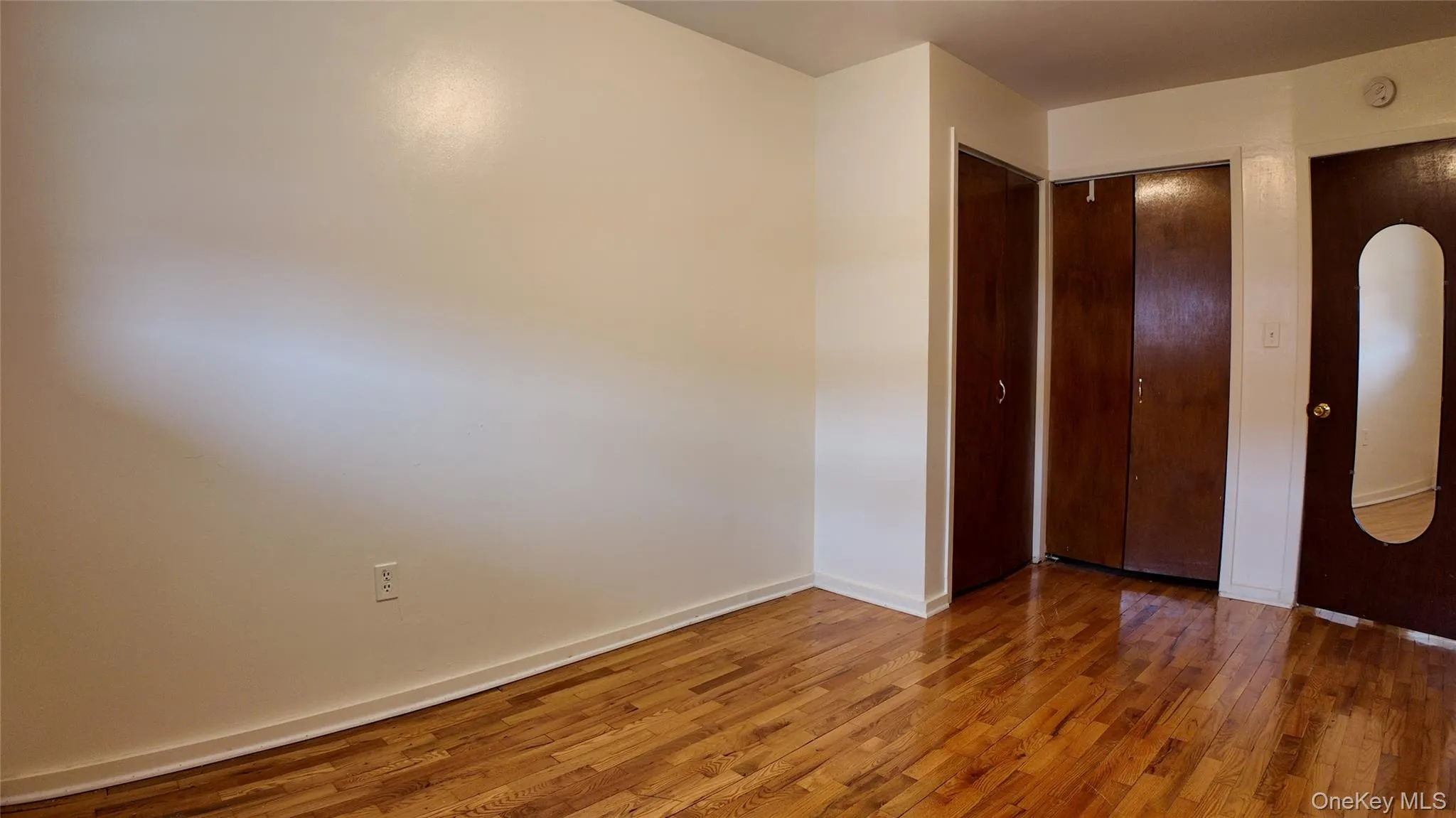Unfurnished bedroom featuring a closet, hardwood / wood-style floors, and arched walkways Unfurnished bedroom featuring a closet, hardwood / wood-style floors, and arched walkways
