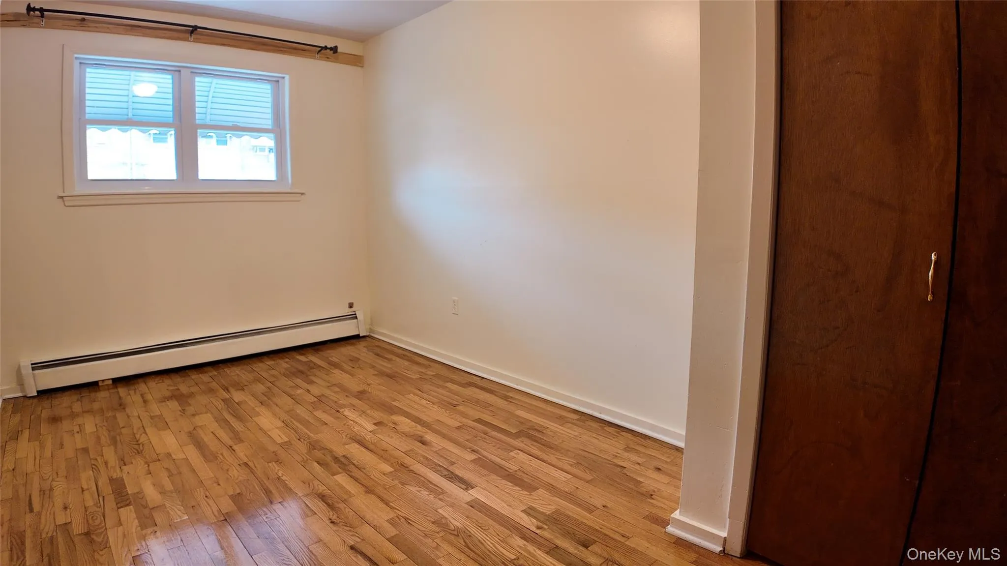 Spare room with a baseboard heating unit and hardwood / wood-style floors Spare room with a baseboard heating unit and hardwood / wood-style floors