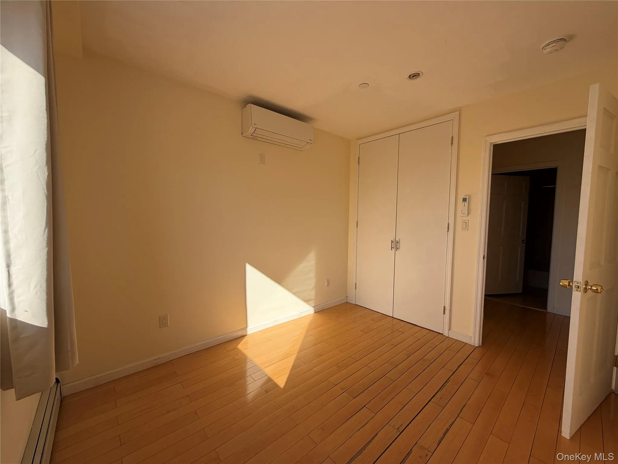 Unfurnished bedroom with a baseboard heating unit, light wood finished floors, and a closet Unfurnished bedroom with a baseboard heating unit, light wood finished floors, and a closet