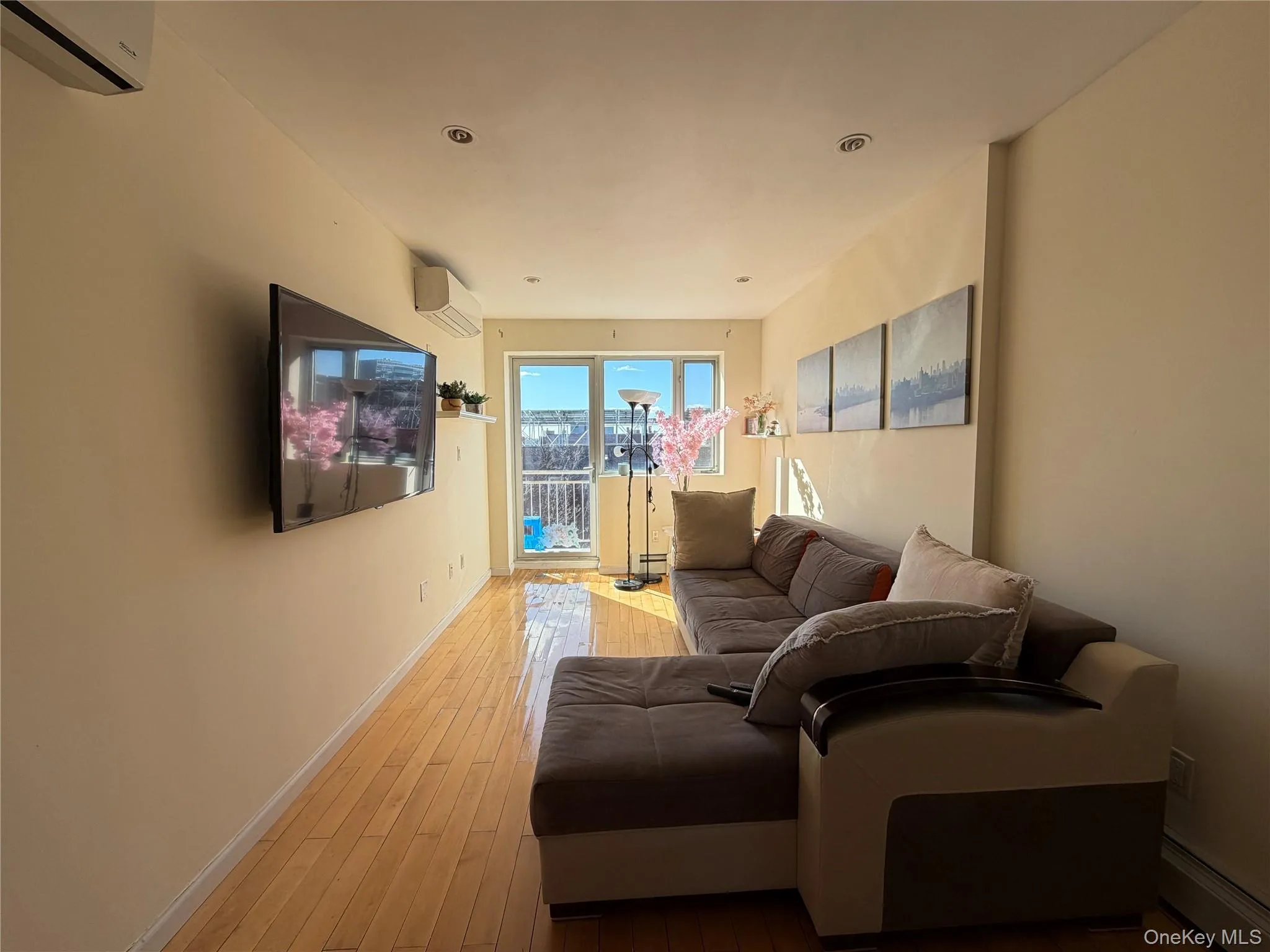 Living room with light wood-style flooring, a wall mounted mini split, and baseboard heating Living room with light wood-style flooring, a wall mounted mini split, and baseboard heating