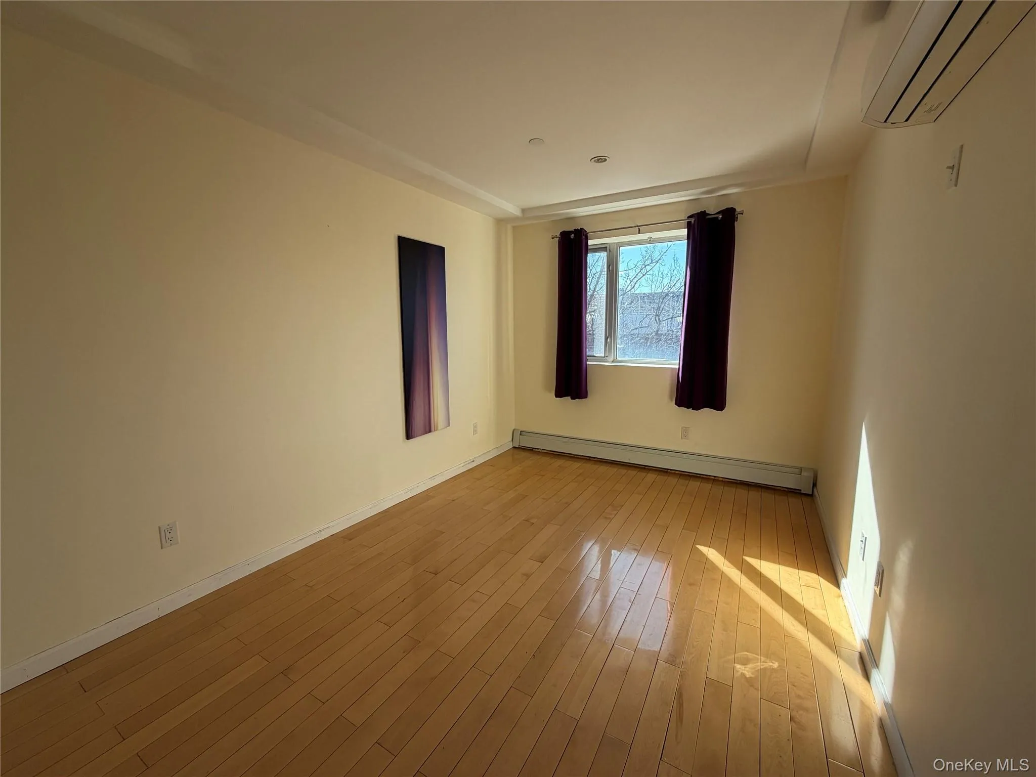 Unfurnished room with a wall mounted mini split, a baseboard radiator, and light wood-style flooring Unfurnished room with a wall mounted mini split, a baseboard radiator, and light wood-style flooring