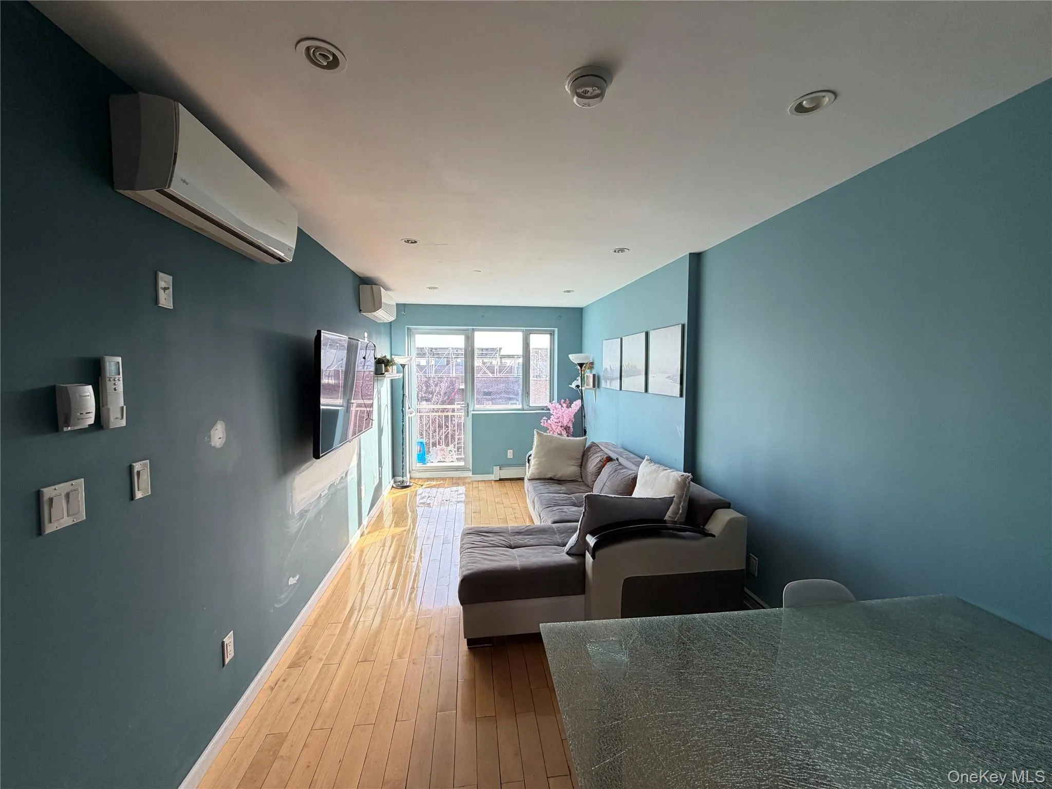 Living area featuring an AC wall unit, hardwood / wood-style flooring, a baseboard heating unit, and recessed lighting Living area featuring an AC wall unit, hardwood / wood-style flooring, a baseboard heating unit, and recessed lighting