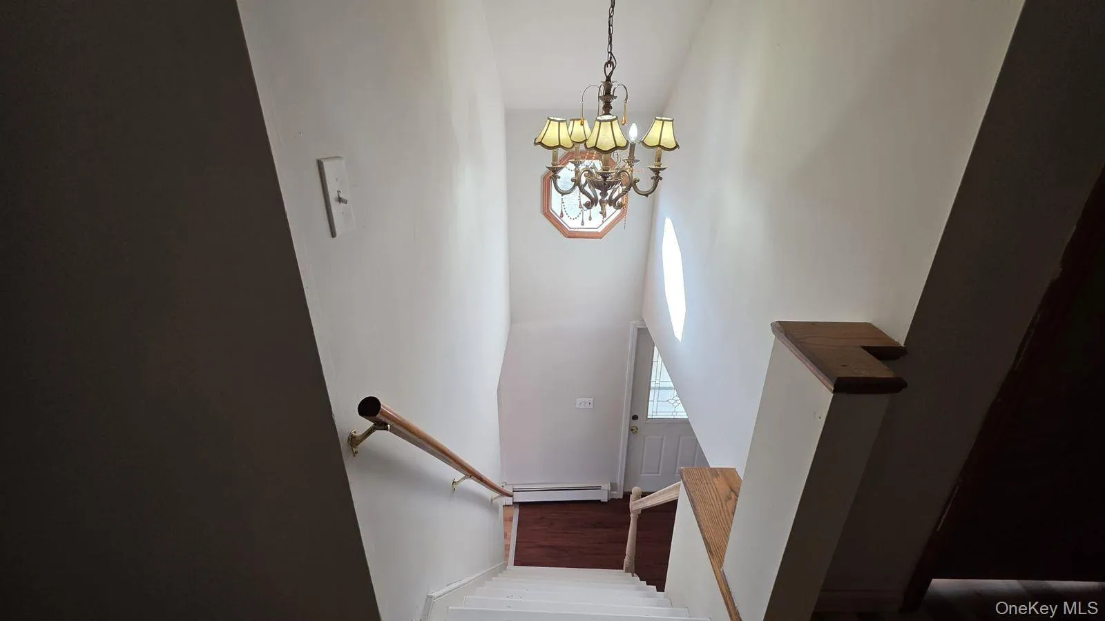 Stairs with a chandelier, a baseboard heating unit, and wood finished floors Stairs with a chandelier, a baseboard heating unit, and wood finished floors
