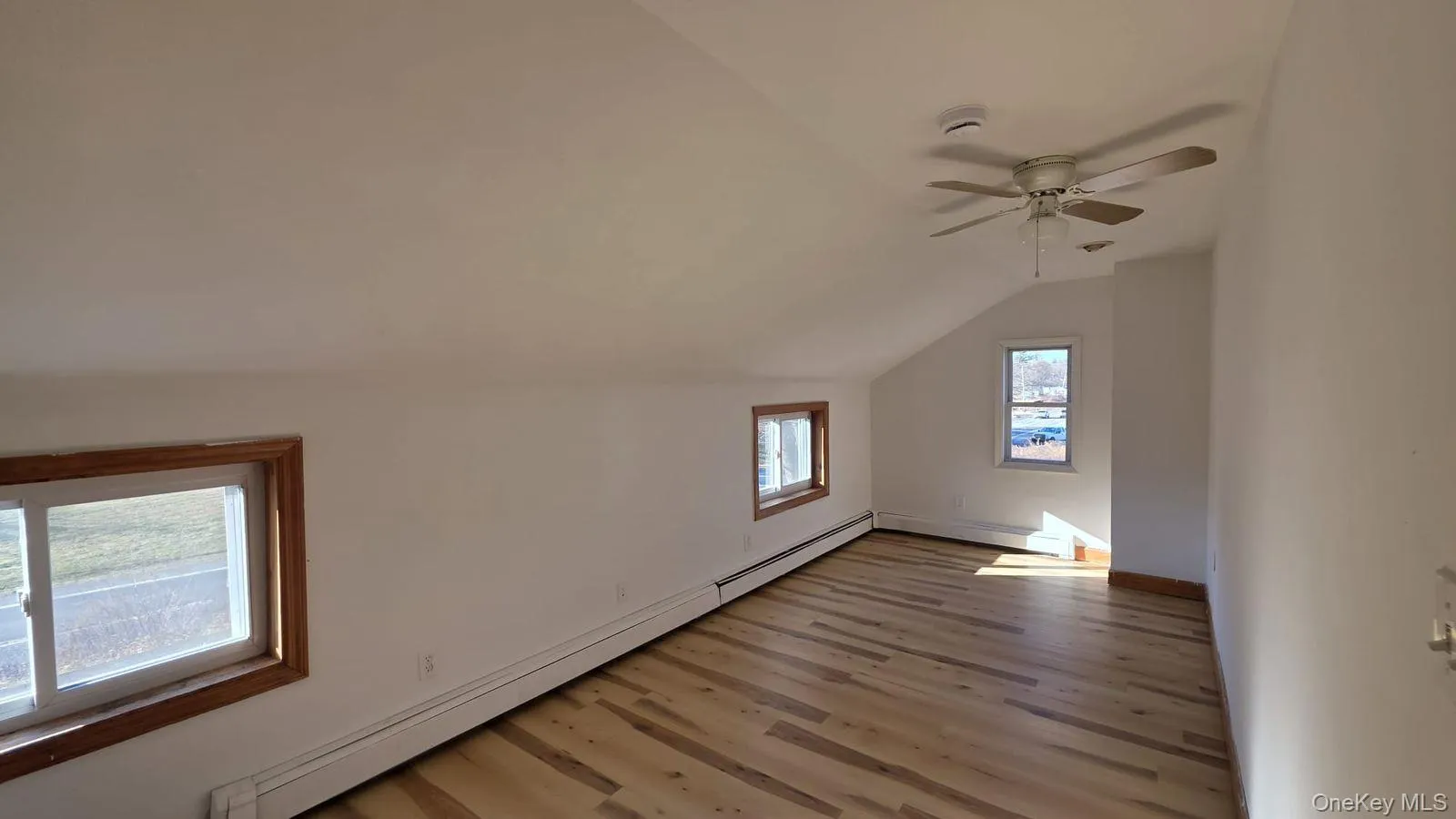 Additional living space with a baseboard radiator, vaulted ceiling, light wood-style floors, a ceiling fan, and a baseboard heating unit Additional living space with a baseboard radiator, vaulted ceiling, light wood-style floors, a ceiling fan, and a baseboard heating unit
