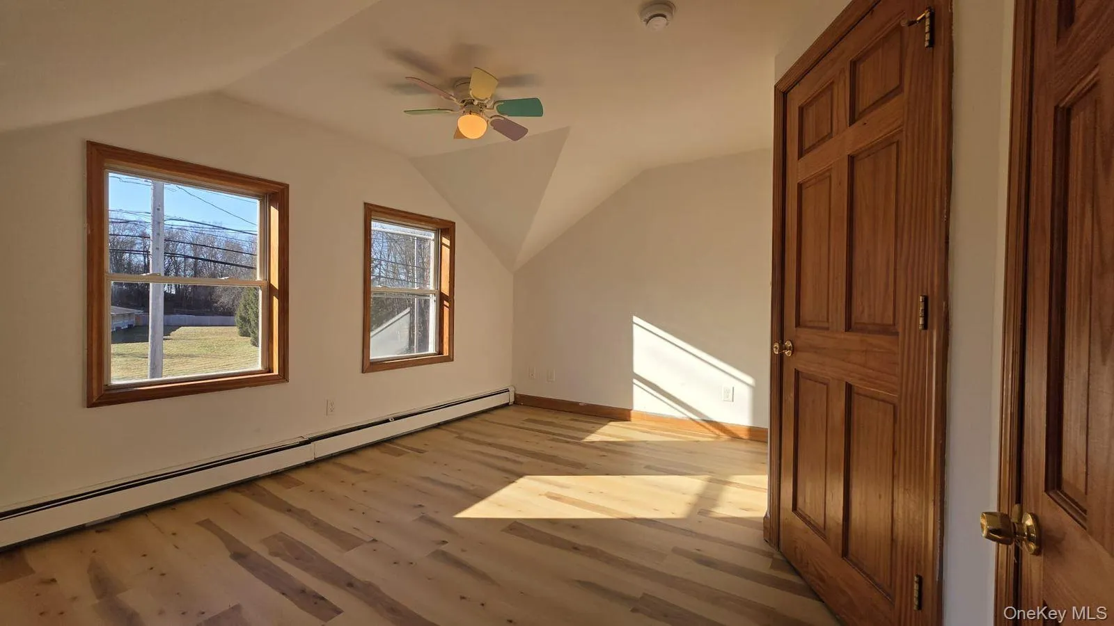 Additional living space featuring baseboard heating, light wood-style flooring, ceiling fan, and lofted ceiling Additional living space featuring baseboard heating, light wood-style flooring, ceiling fan, and lofted ceiling
