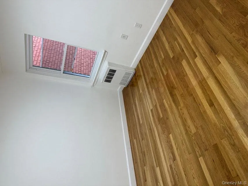 Spare room with wood finished floors and radiator Spare room with wood finished floors and radiator