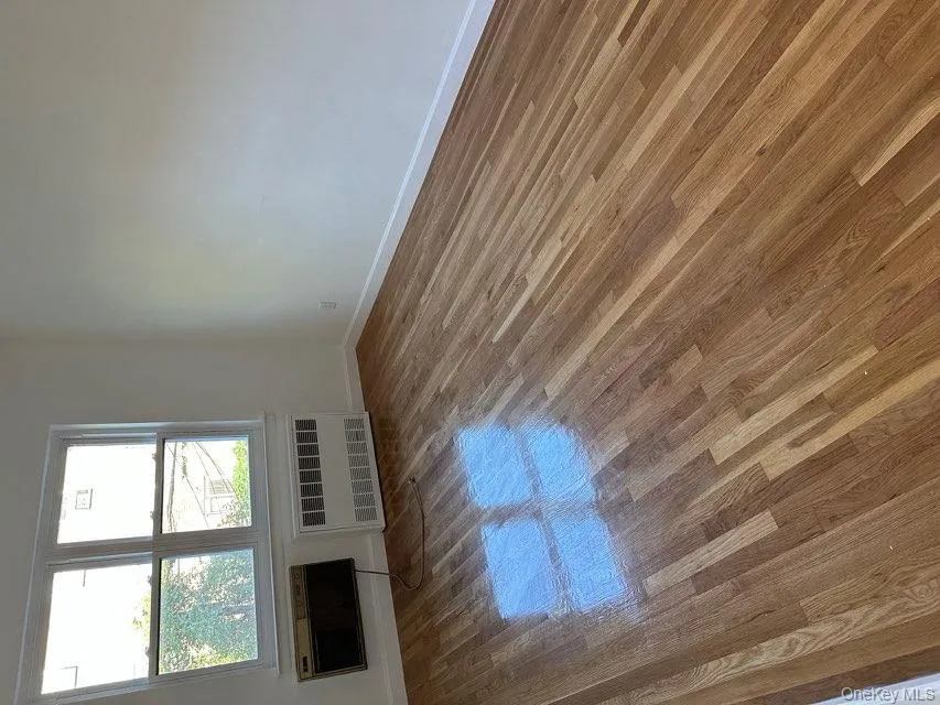 Unfurnished room featuring radiator heating unit and wood finished floors Unfurnished room featuring radiator heating unit and wood finished floors