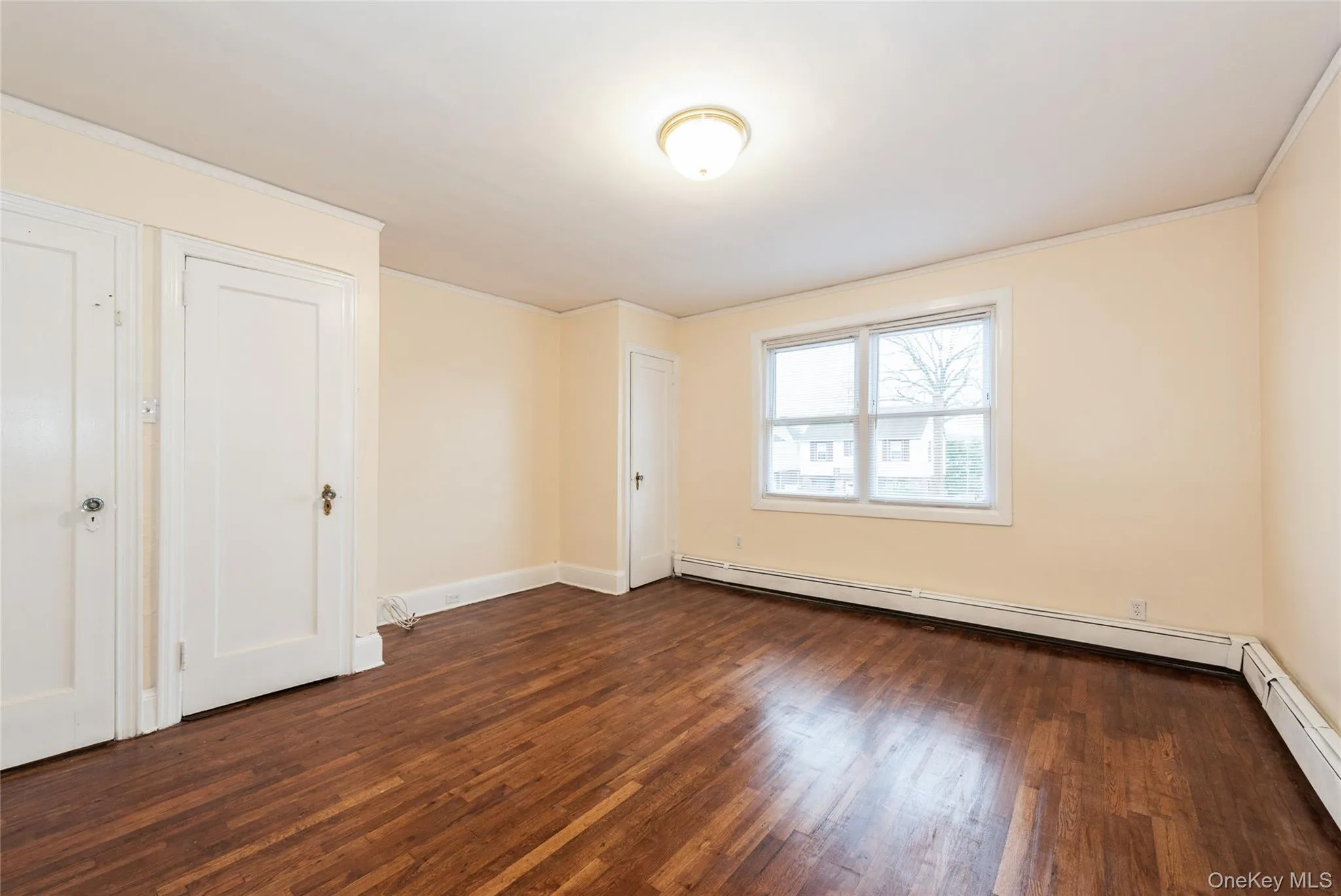 Primary Bedroom featuring hardwood finished floors, baseboard heating, and ornamental molding. Primary Bedroom featuring hardwood finished floors, baseboard heating, and ornamental molding.