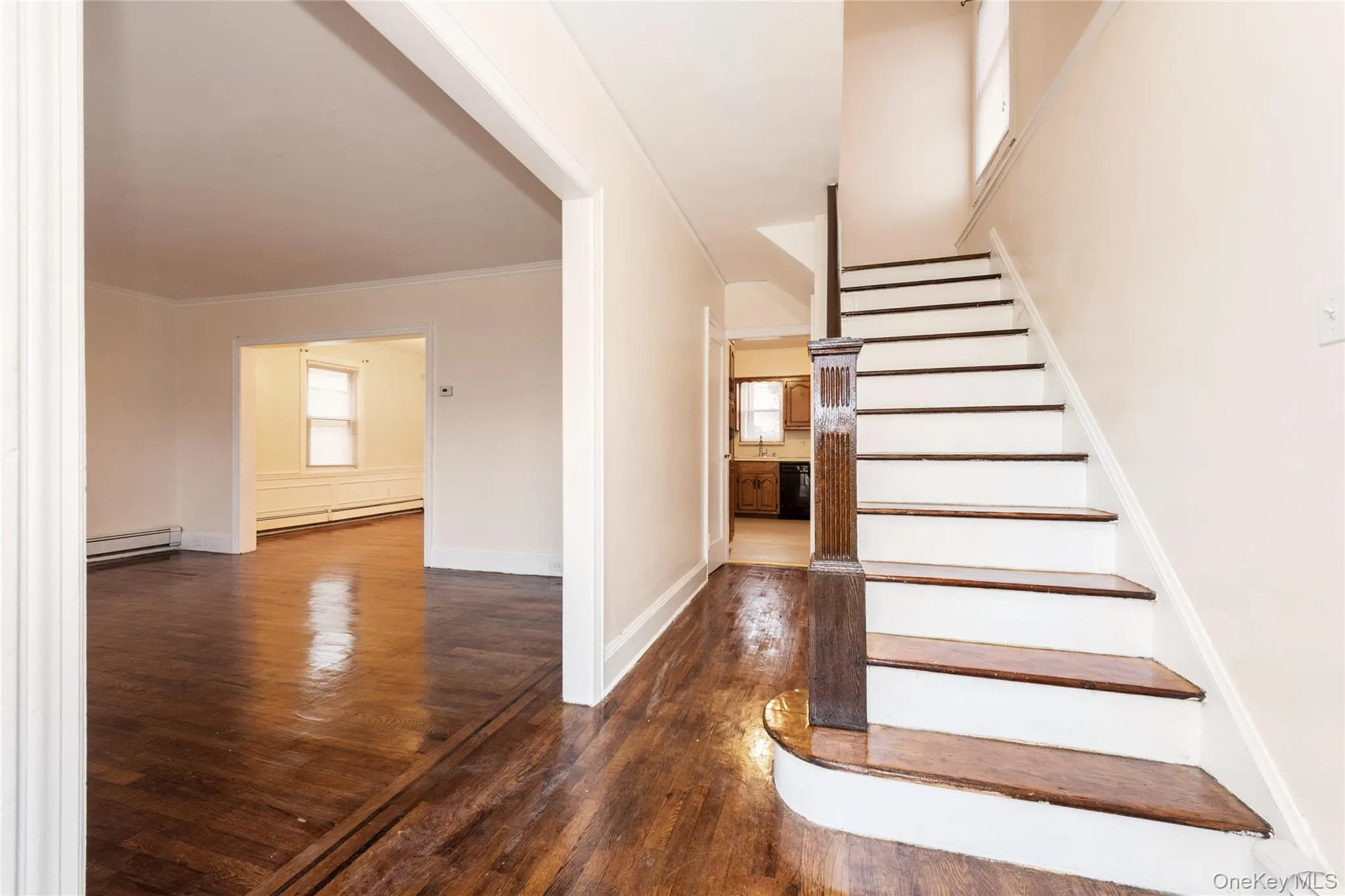 Stairs with hardwood / wood flooring, healthy amount of natural light, baseboard heating, and ornamental molding. Stairs with hardwood / wood flooring, healthy amount of natural light, baseboard heating, and ornamental molding.