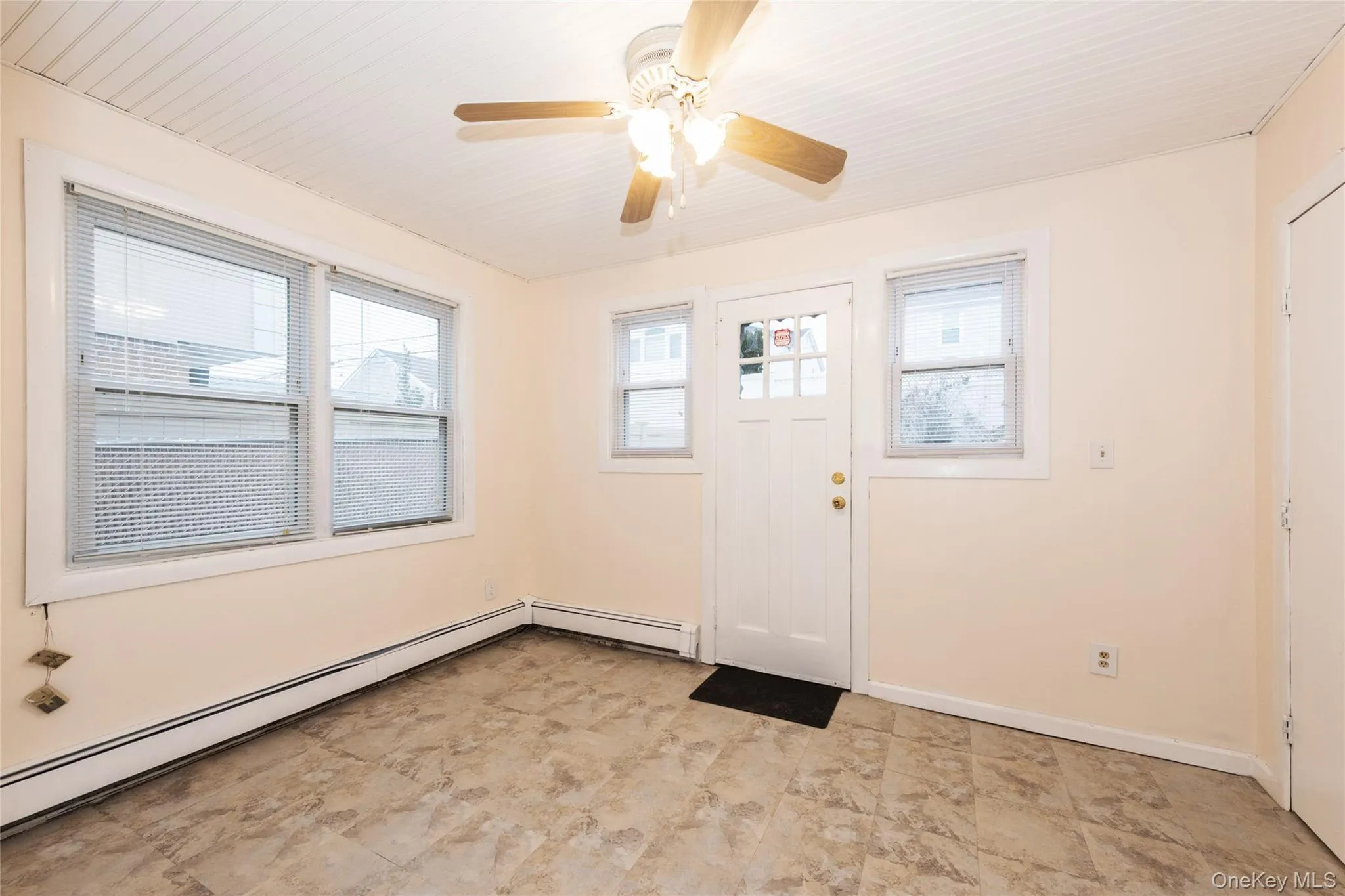 Den with rear entrance, baseboard radiator, and a ceiling fan. Den with rear entrance, baseboard radiator, and a ceiling fan.