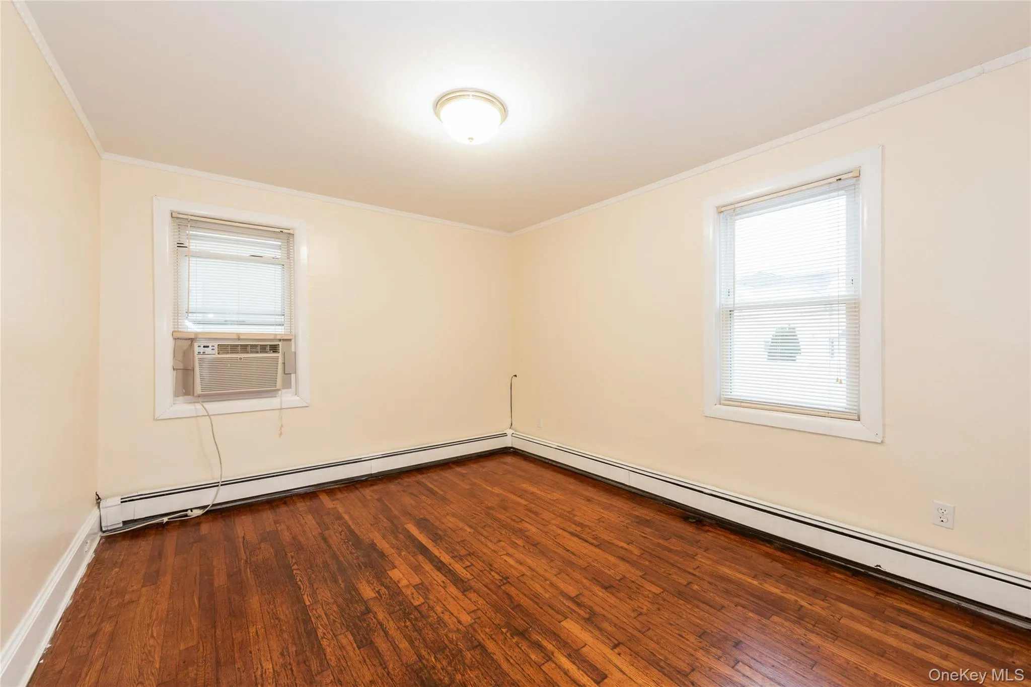 2nd Bedroom with hardwood flooring, crown molding, and a baseboard radiator, and A/C unit. 2nd Bedroom with hardwood flooring, crown molding, and a baseboard radiator, and A/C unit.
