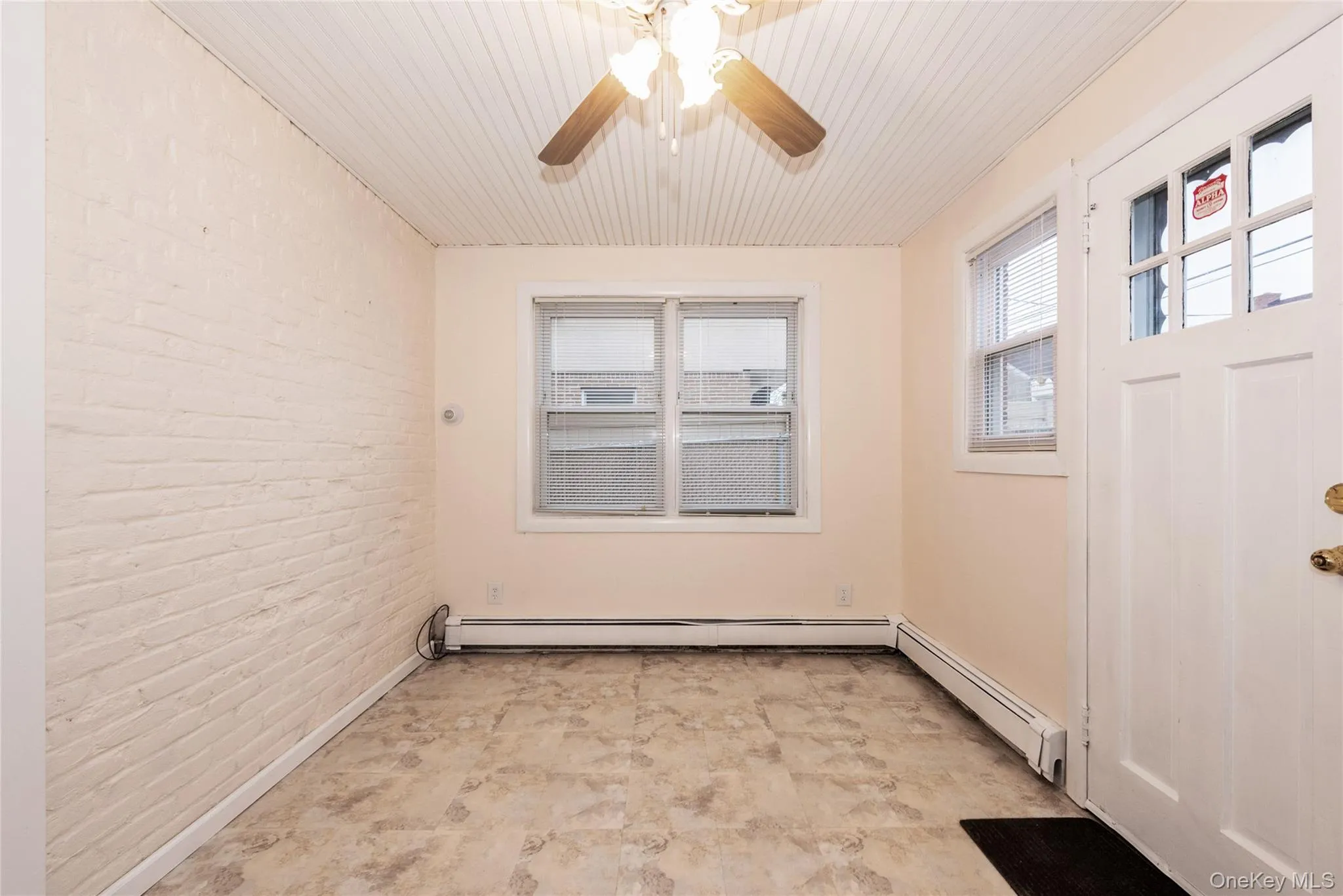 Den with rear entrance, baseboard radiator, and a ceiling fan. Den with rear entrance, baseboard radiator, and a ceiling fan.