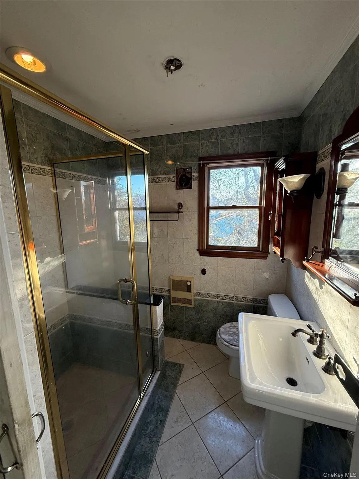 Bathroom with tile walls, a shower stall, light tile patterned flooring, and heating unit Bathroom with tile walls, a shower stall, light tile patterned flooring, and heating unit