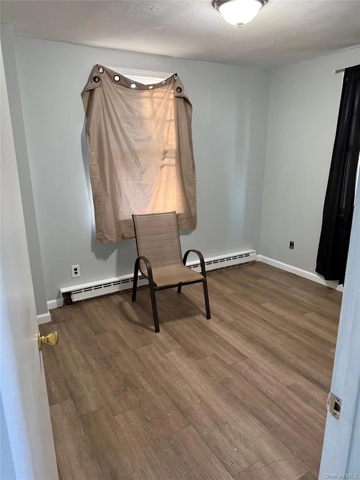 Unfurnished bedroom with wood finished floors and a baseboard radiator Unfurnished bedroom with wood finished floors and a baseboard radiator