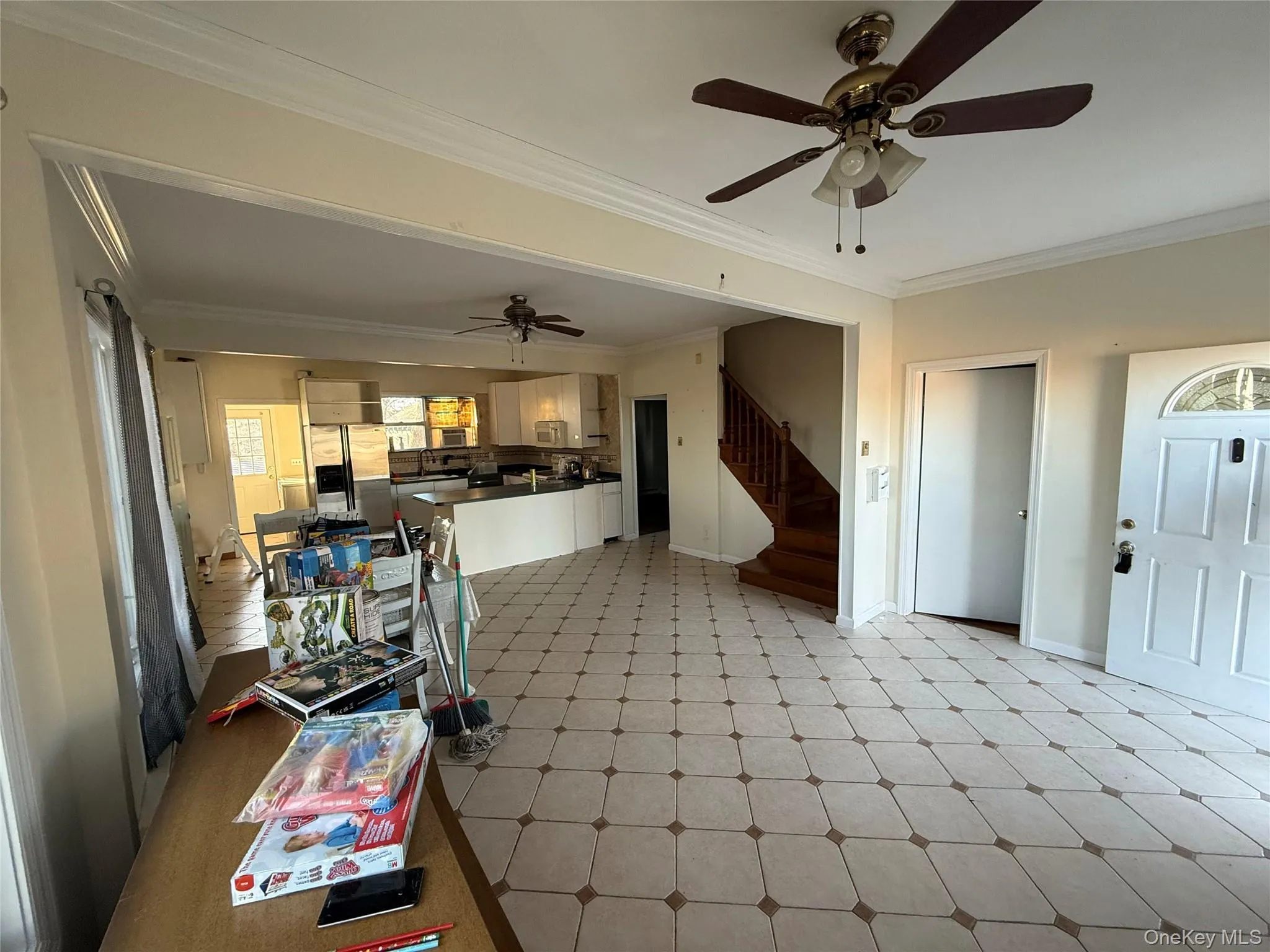 Kitchen featuring dark countertops, ornamental molding, ceiling fan, light floors, and stainless steel refrigerator with ice dispenser Kitchen featuring dark countertops, ornamental molding, ceiling fan, light floors, and stainless steel refrigerator with ice dispenser