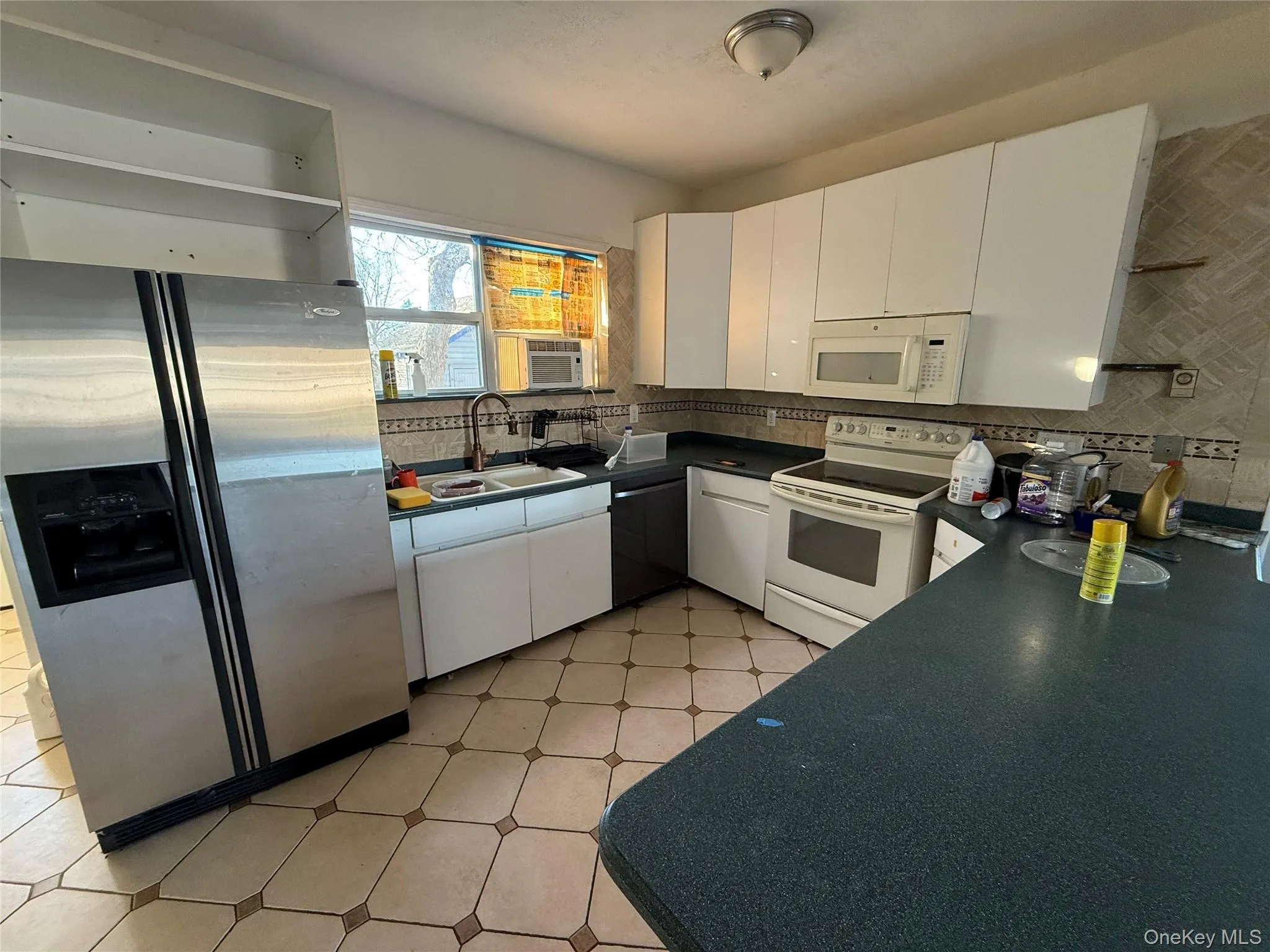 Kitchen with white appliances, light flooring, white cabinetry, and dark countertops Kitchen with white appliances, light flooring, white cabinetry, and dark countertops