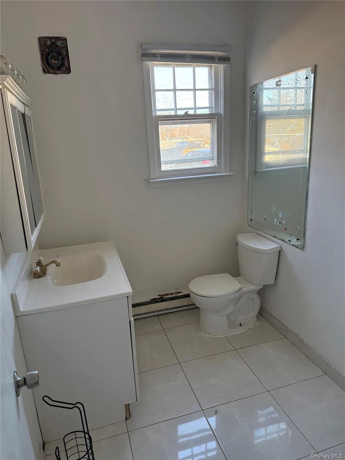 Half bathroom featuring vanity, light tile patterned floors, and a baseboard radiator Half bathroom featuring vanity, light tile patterned floors, and a baseboard radiator