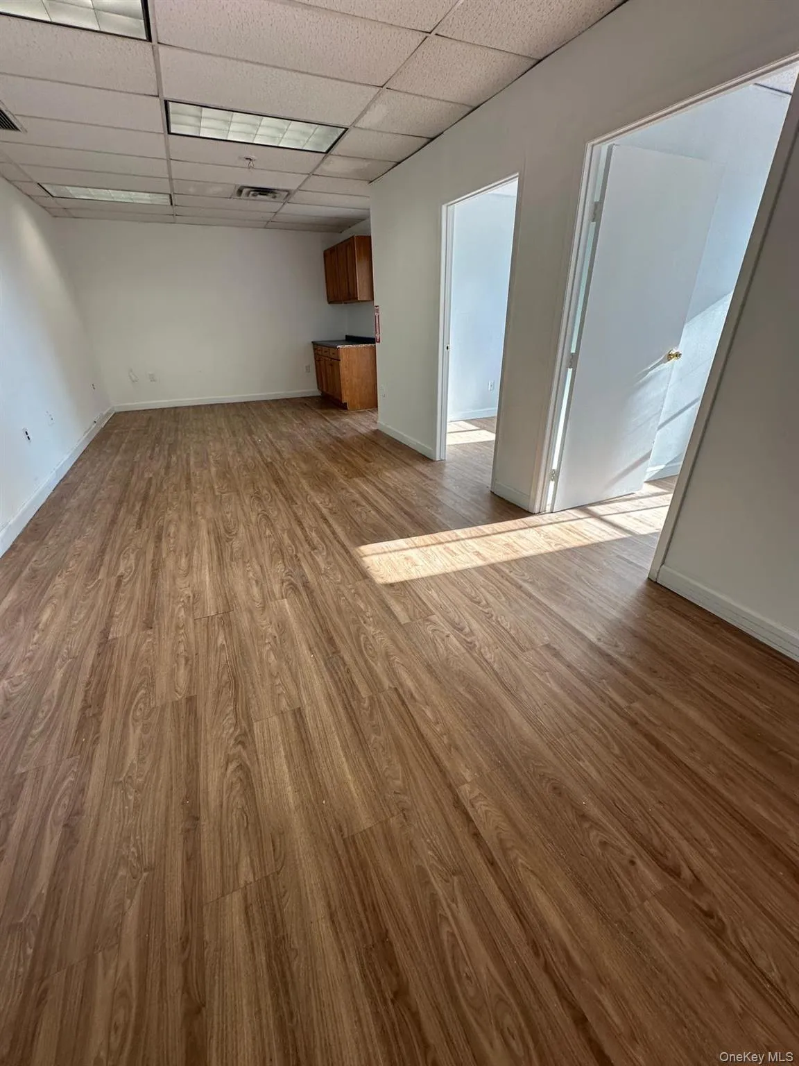 Unfurnished living room featuring a drop ceiling and light wood-style flooring Unfurnished living room featuring a drop ceiling and light wood-style flooring