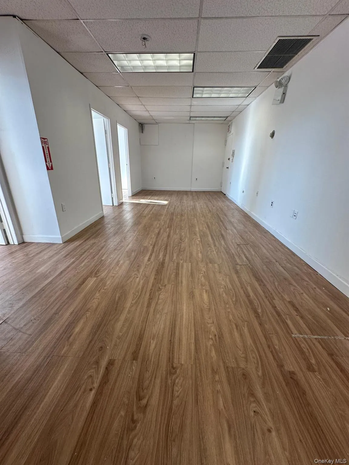 Unfurnished room featuring light wood-type flooring and a paneled ceiling Unfurnished room featuring light wood-type flooring and a paneled ceiling
