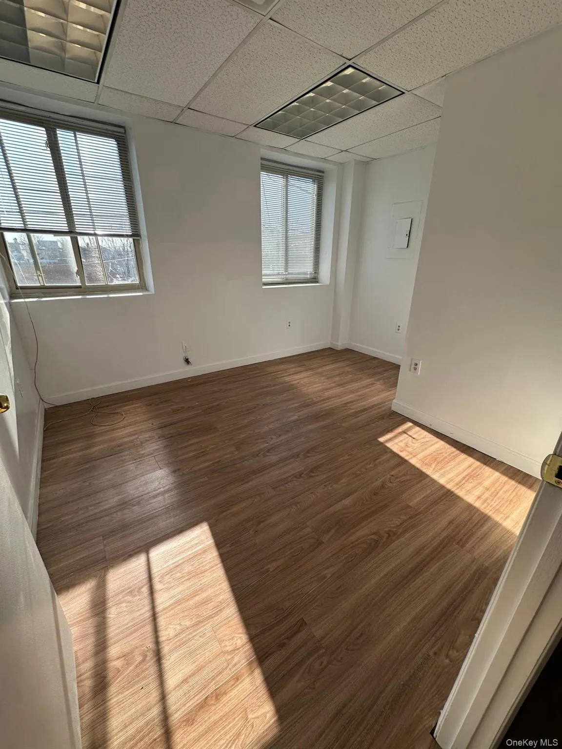 Empty room with dark wood-style flooring and a drop ceiling Empty room with dark wood-style flooring and a drop ceiling