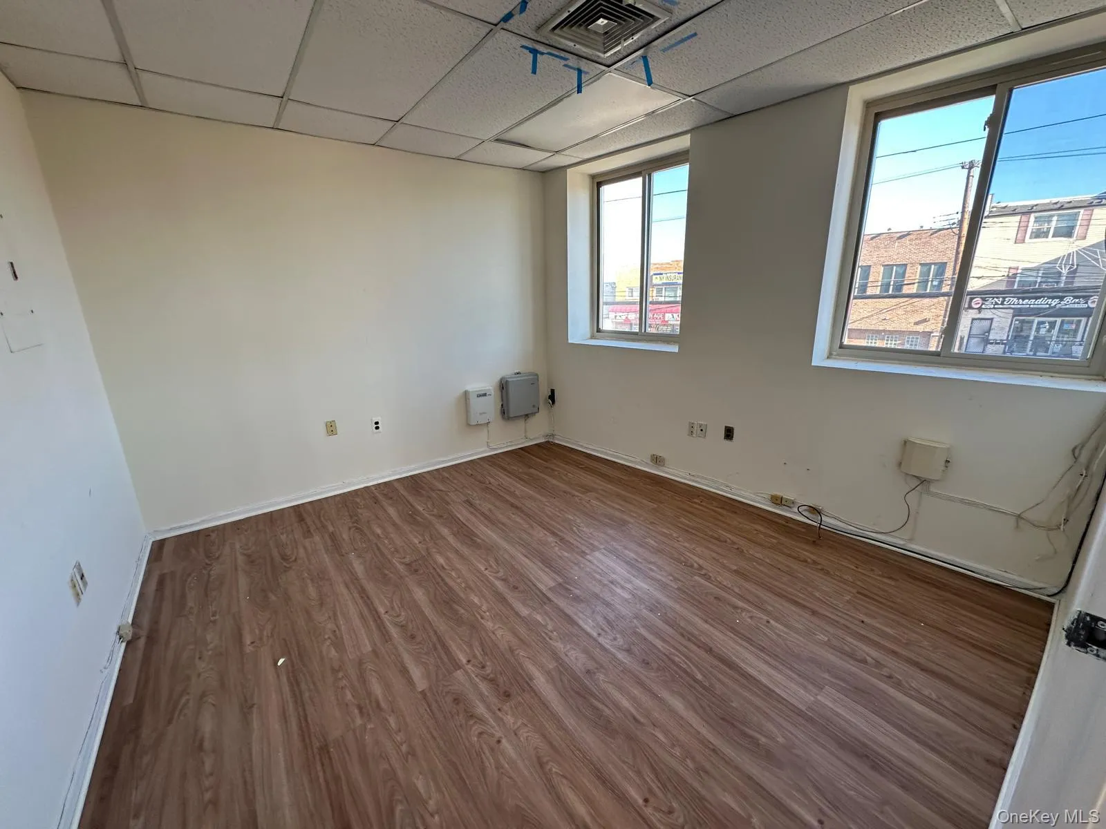 Spare room with a drop ceiling and wood finished floors Spare room with a drop ceiling and wood finished floors