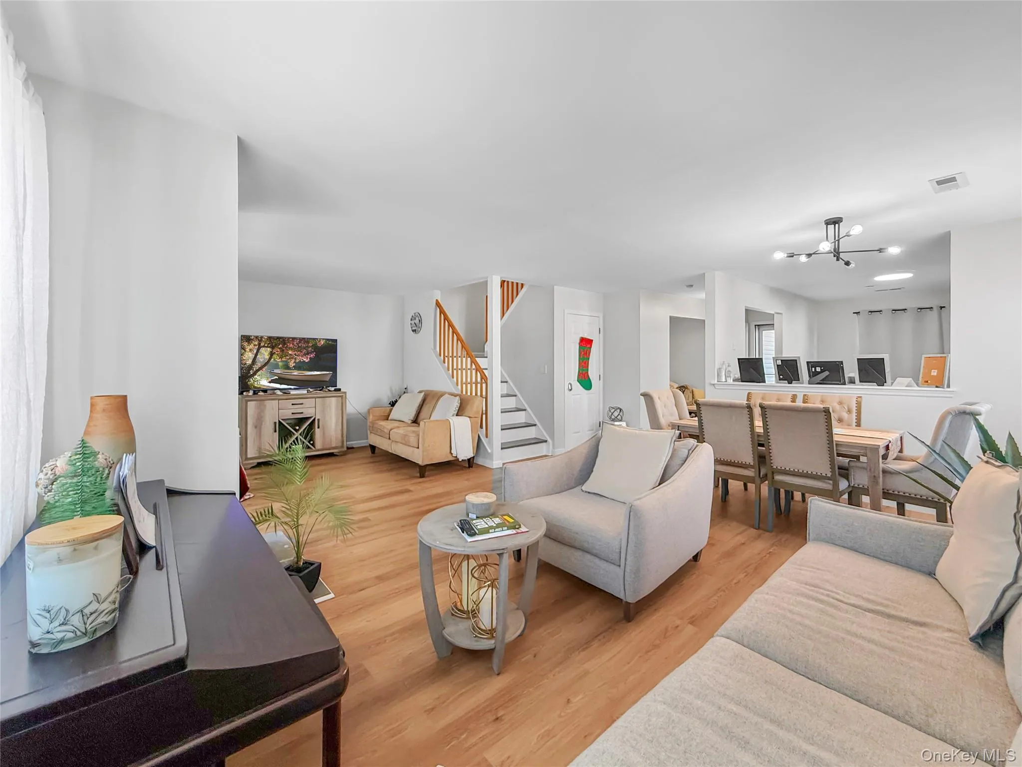 Living area with a chandelier, light wood-style flooring, and stairs Living area with a chandelier, light wood-style flooring, and stairs