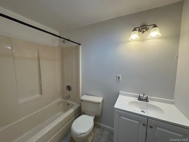 Bathroom with vanity, washtub / shower combination, and light tile patterned flooring Bathroom with vanity, washtub / shower combination, and light tile patterned flooring