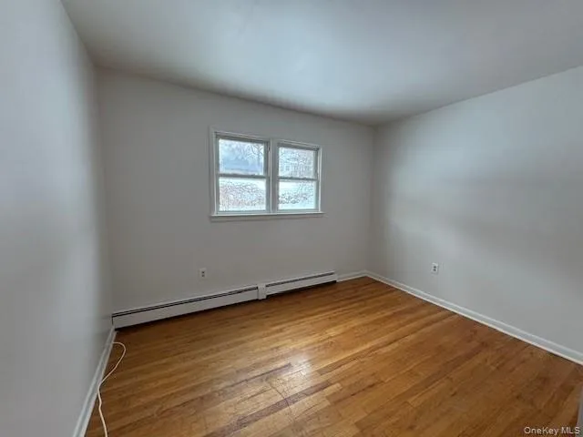 Unfurnished room featuring light wood-style floors and a baseboard radiator Unfurnished room featuring light wood-style floors and a baseboard radiator