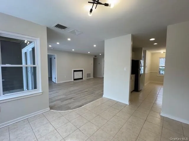Unfurnished living room featuring light tile patterned floors, recessed lighting, and a fireplace Unfurnished living room featuring light tile patterned floors, recessed lighting, and a fireplace