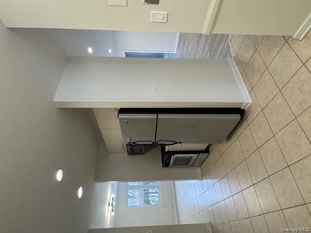 Kitchen featuring freestanding refrigerator, recessed lighting, light tile patterned floors, range, and white cabinetry Kitchen featuring freestanding refrigerator, recessed lighting, light tile patterned floors, range, and white cabinetry