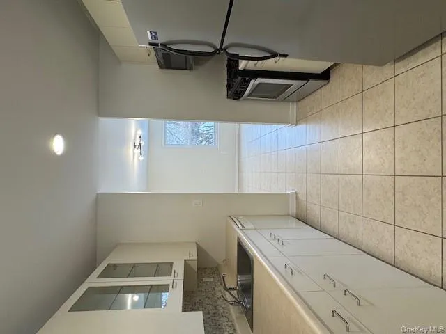 Kitchen featuring white cabinetry, fridge, stove, glass insert cabinets, and light countertops Kitchen featuring white cabinetry, fridge, stove, glass insert cabinets, and light countertops