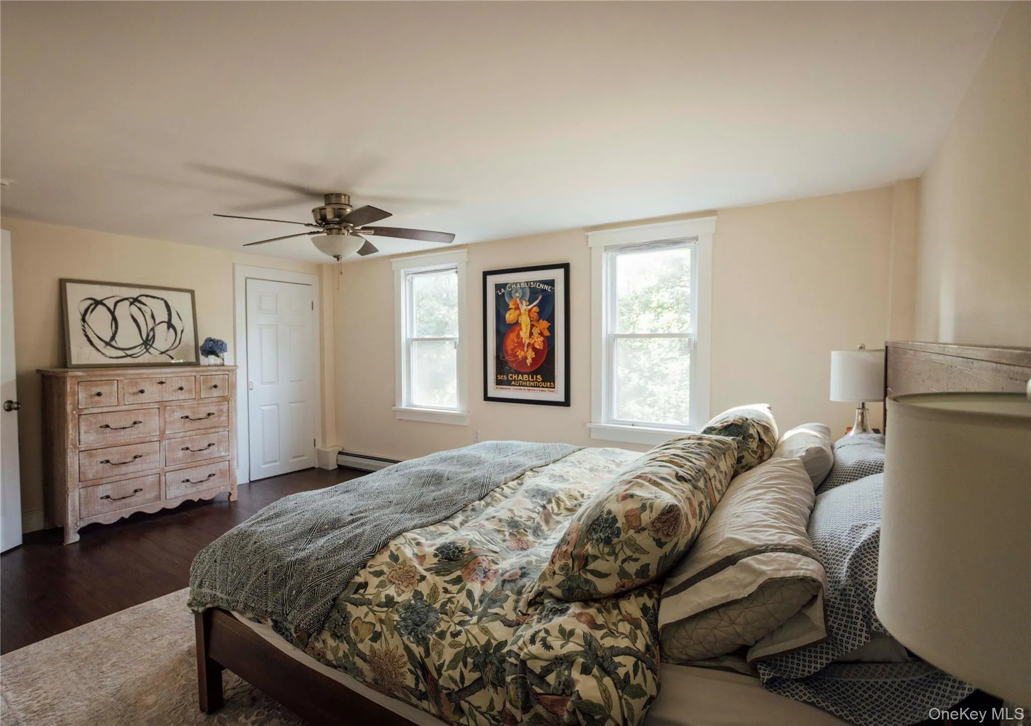Bedroom featuring dark wood-type flooring, a ceiling fan, a closet, and a baseboard heating unit Bedroom featuring dark wood-type flooring, a ceiling fan, a closet, and a baseboard heating unit