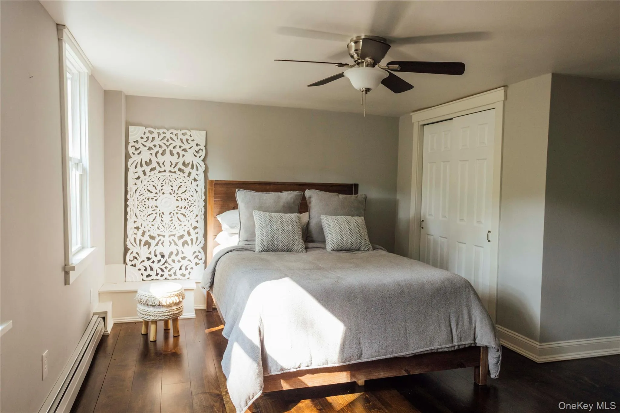 Bedroom with baseboard heating, wood finished floors, ceiling fan, and a closet Bedroom with baseboard heating, wood finished floors, ceiling fan, and a closet