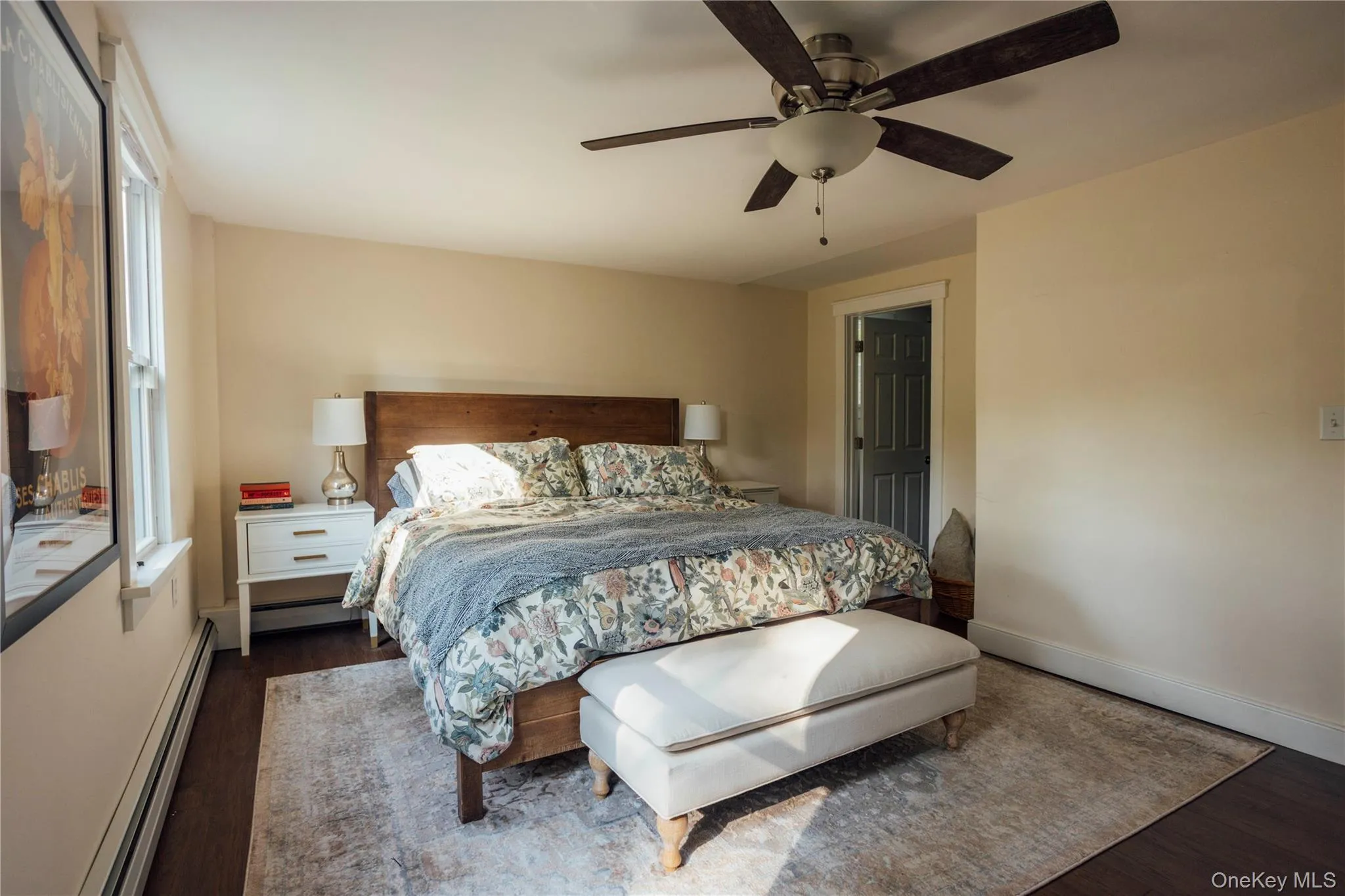 Bedroom featuring baseboard heating, dark wood-type flooring, and ceiling fan Bedroom featuring baseboard heating, dark wood-type flooring, and ceiling fan
