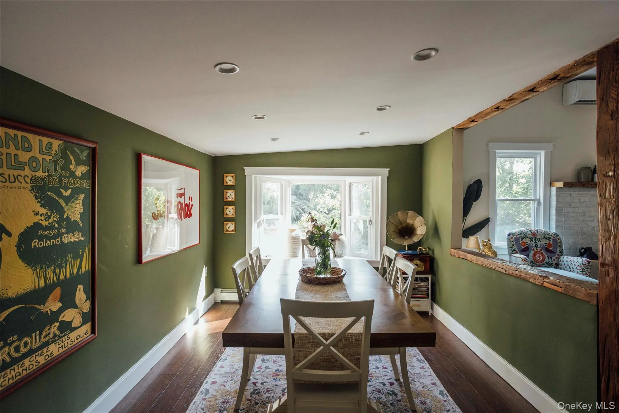 Dining space featuring healthy amount of natural light, wood finished floors, and a wall mounted air conditioner Dining space featuring healthy amount of natural light, wood finished floors, and a wall mounted air conditioner