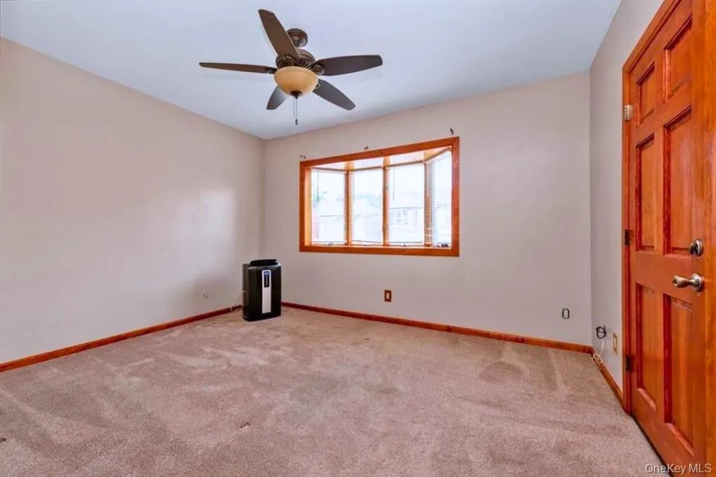 Unfurnished room with light colored carpet and a ceiling fan Unfurnished room with light colored carpet and a ceiling fan