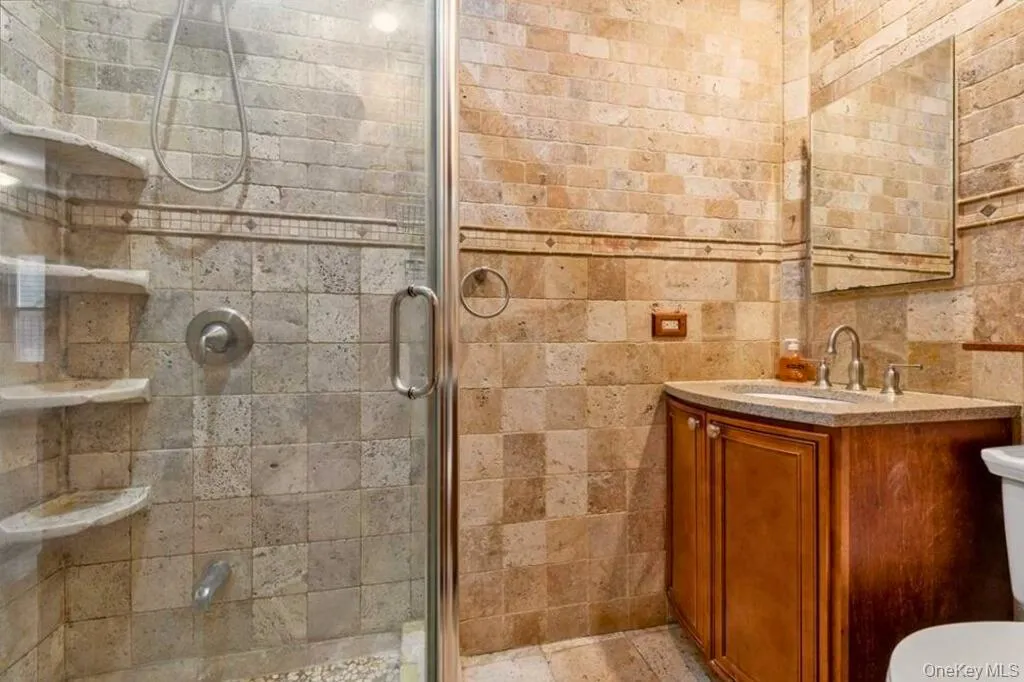 Full bath featuring vanity, a stall shower, and tile walls Full bath featuring vanity, a stall shower, and tile walls