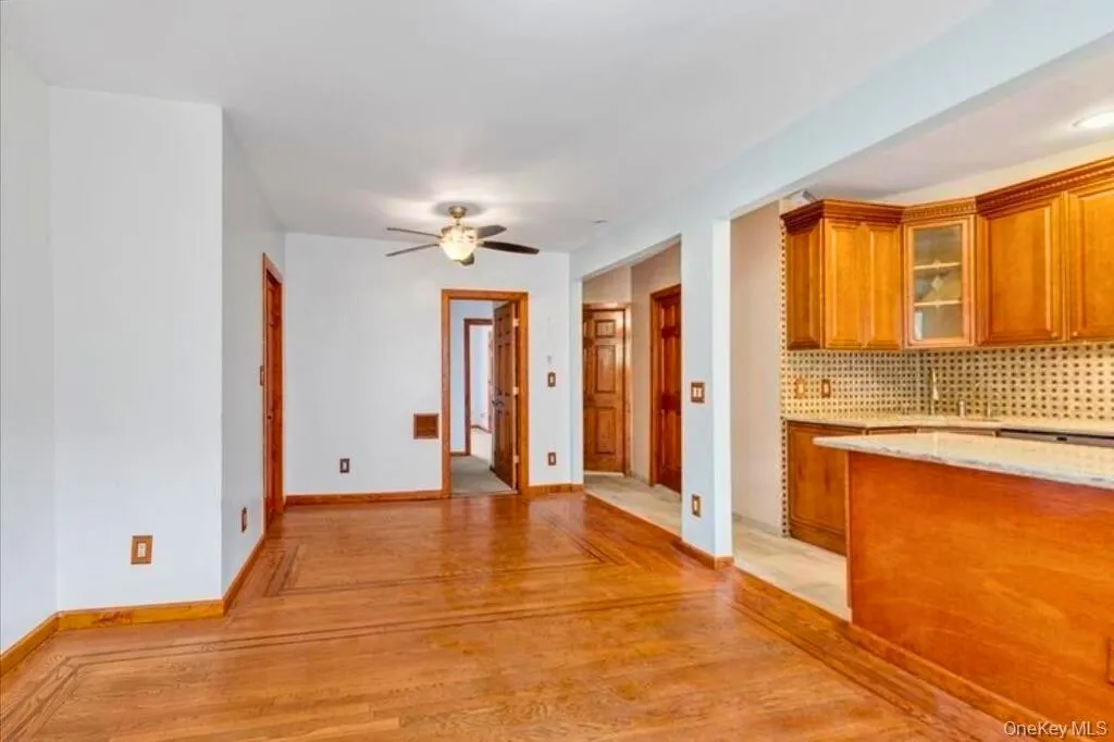 Kitchen with brown cabinets, backsplash, glass insert cabinets, light wood-style floors, and light stone counters Kitchen with brown cabinets, backsplash, glass insert cabinets, light wood-style floors, and light stone counters